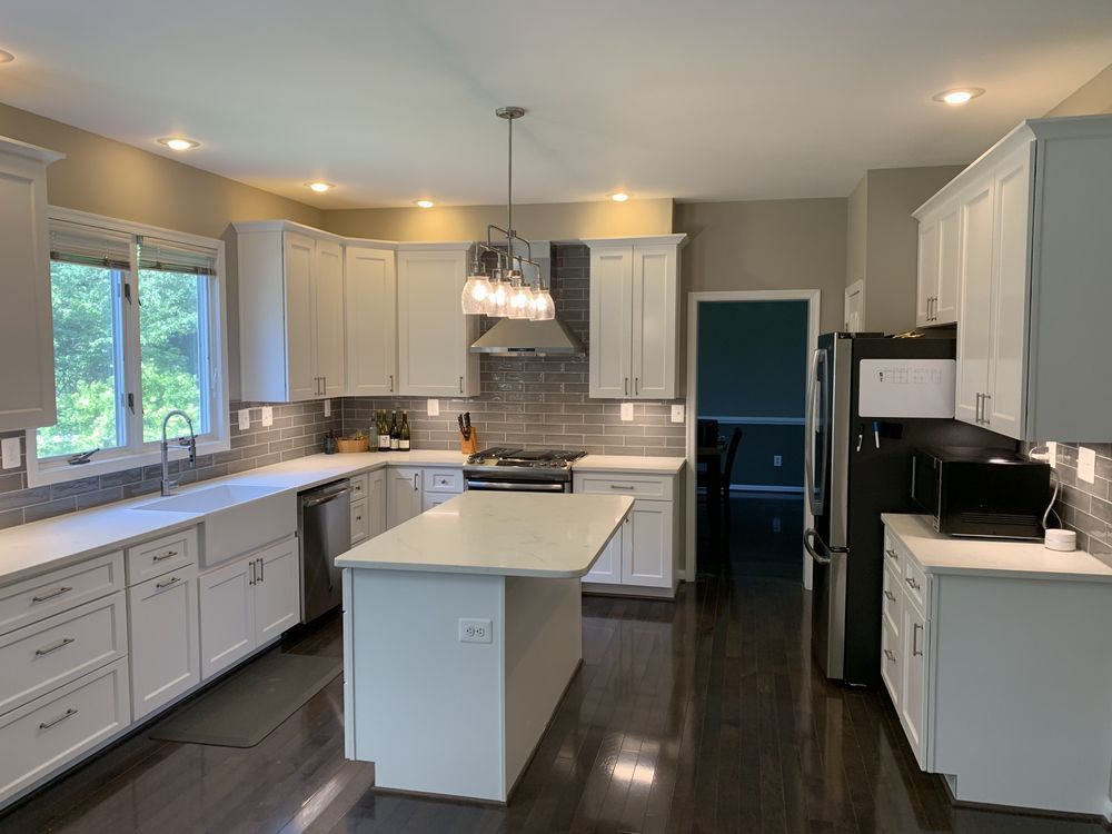 White kitchen with island, cabinets, stainless steel appliances, and dark wood floors.