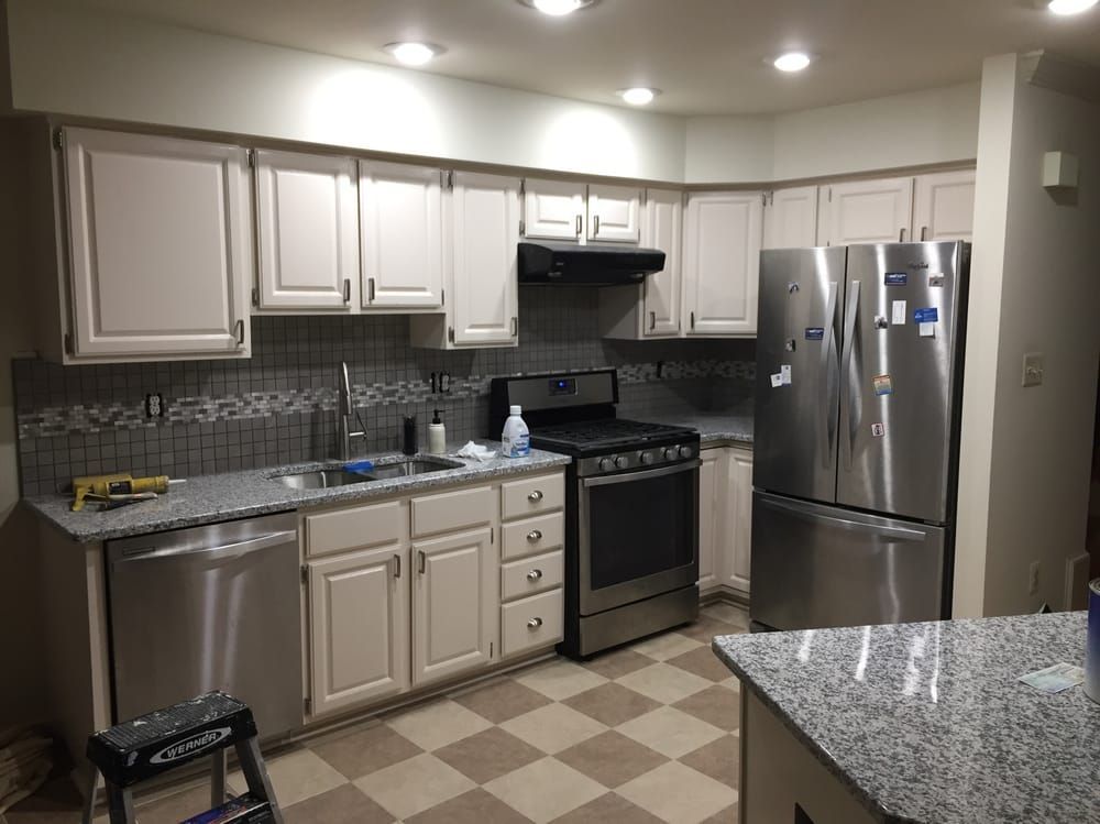 Kitchen with off-white cabinets, stainless steel appliances, a tiled backsplash, and checkered floor.