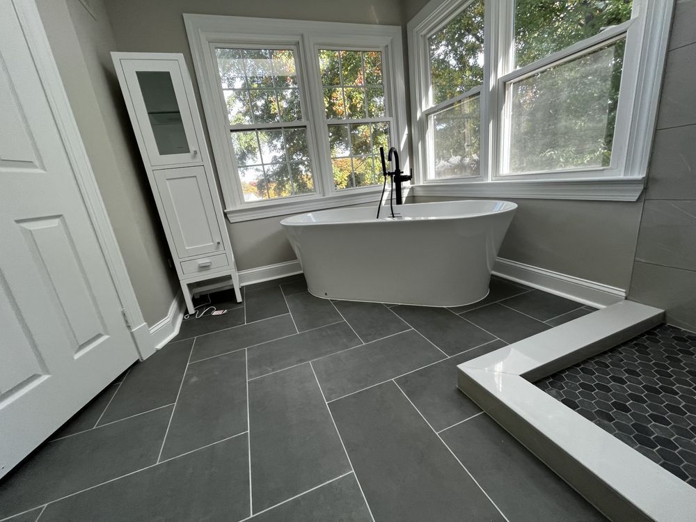 Bathroom with freestanding tub, tiled floor, and window.