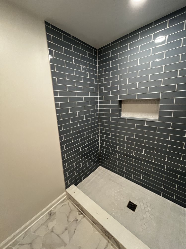 Corner shower with dark blue subway tiles and a niche.