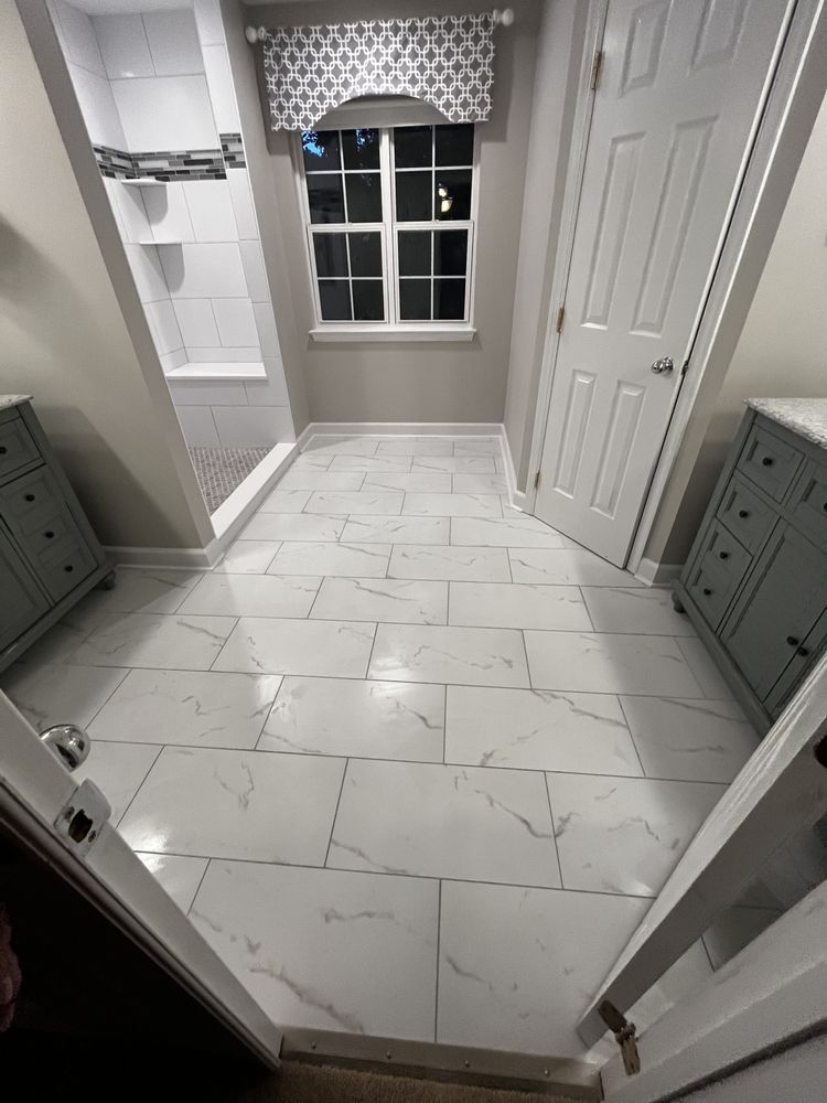 Bathroom with white marble floor, shower, window with valance, gray cabinets, and white doors.