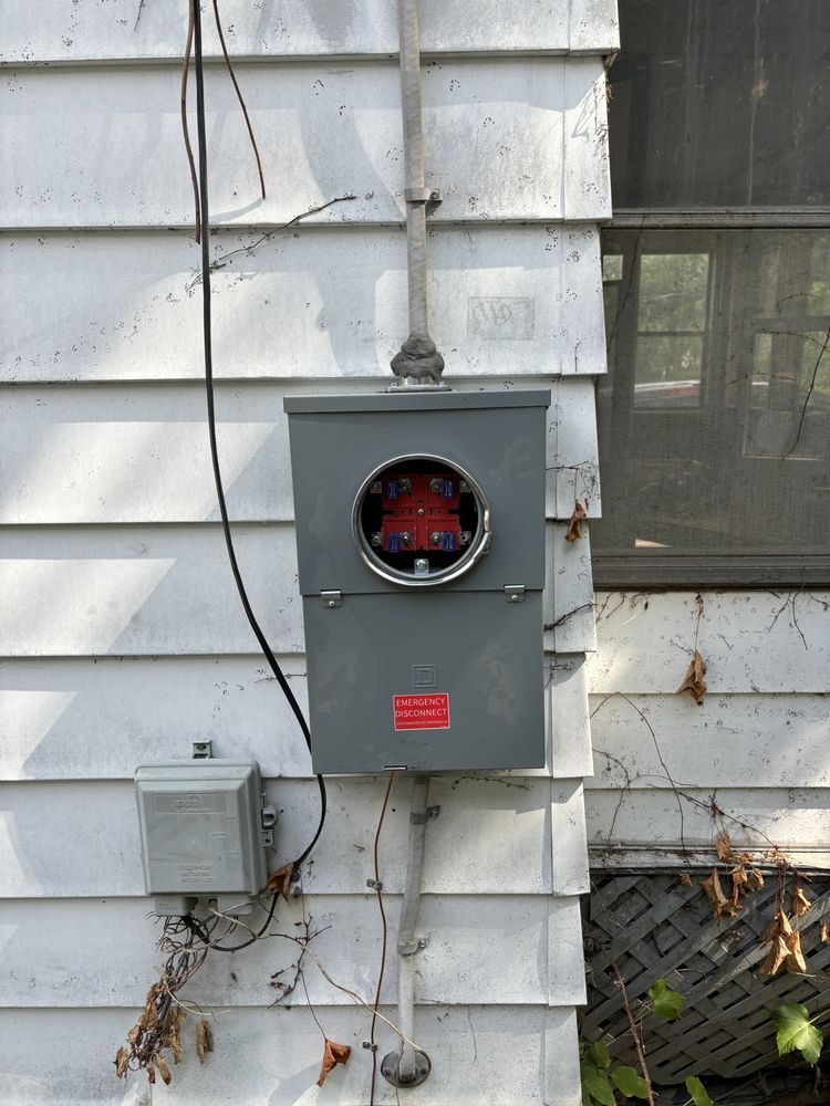 An electrical box is attached to the side of a house.