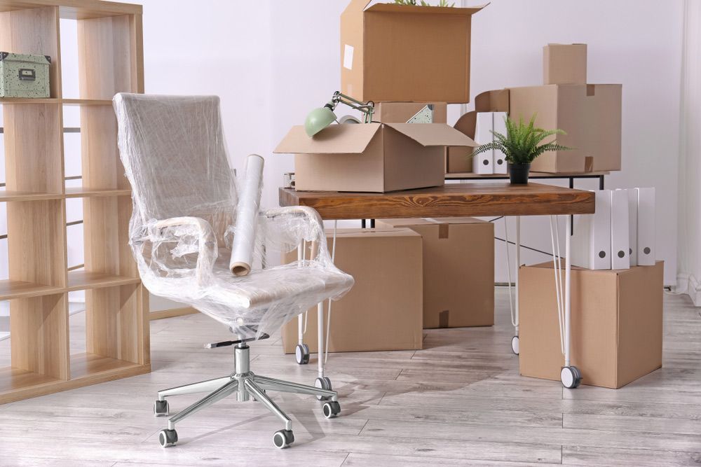 A Chair is Wrapped in Plastic in an Office Surrounded by Cardboard Boxes — Davis Removals & Storage in Victoria Point, QLD
