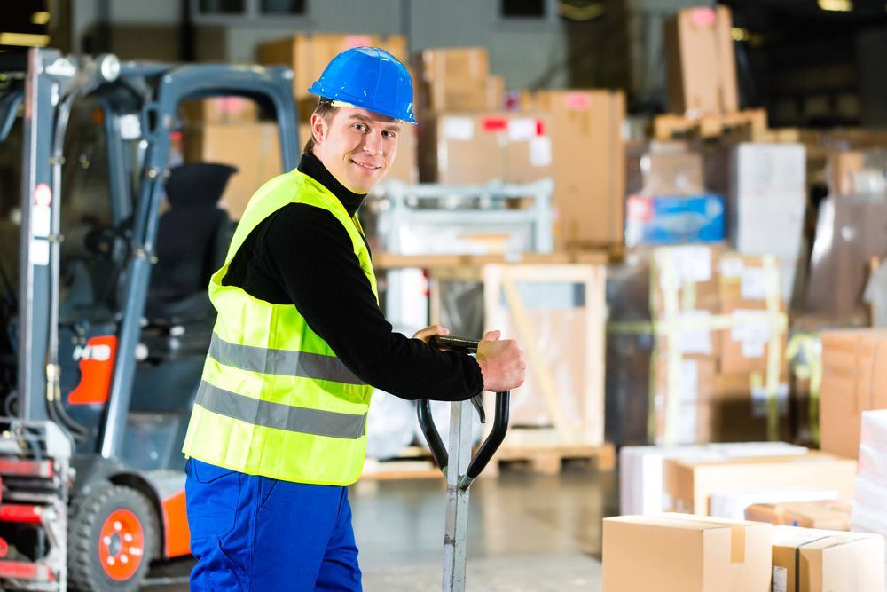 A Man is Pushing a Hand Truck in a Warehouse — Davis Removals & Storage in Gold Coast, QLD