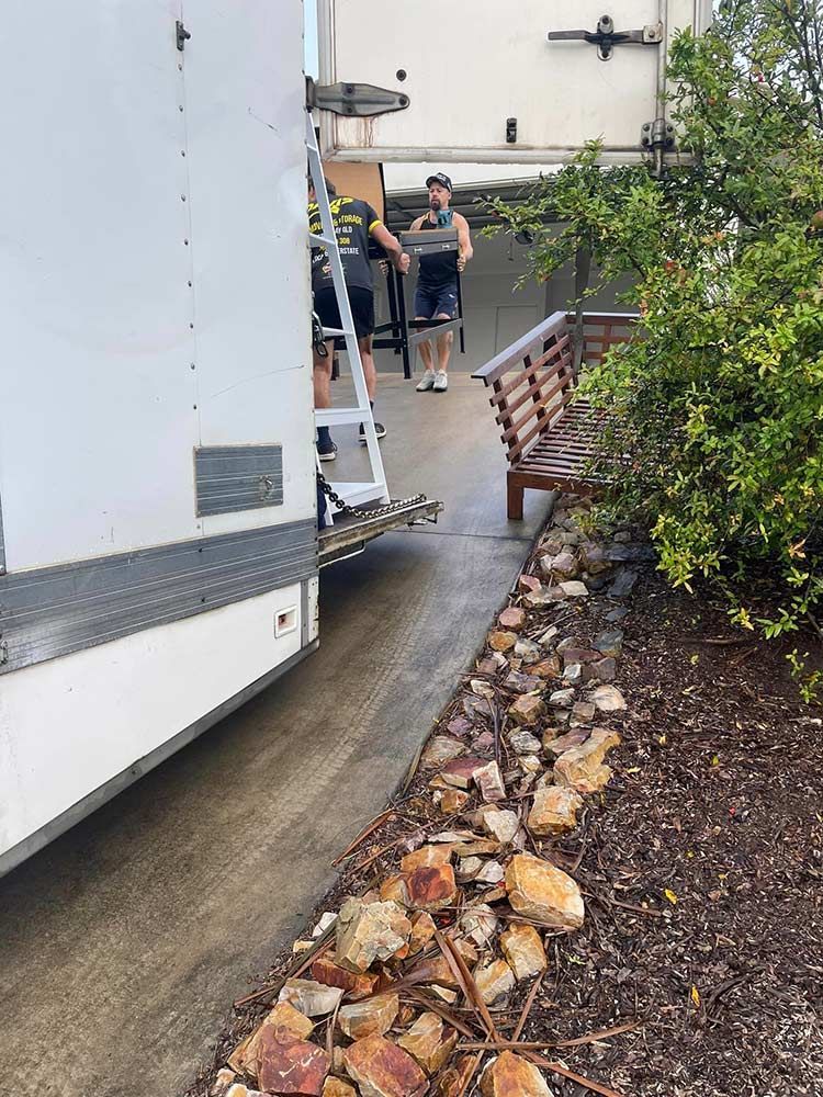 A White Truck is Parked in a Driveway Next to a Bench — Davis Removals & Storage in Chermside, QLD
