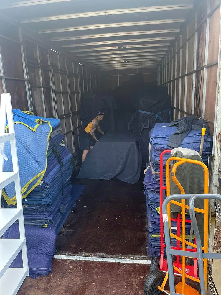 A Man is Loading a Table Into a Moving Truck — Davis Removals & Storage in Dundowran, QLD