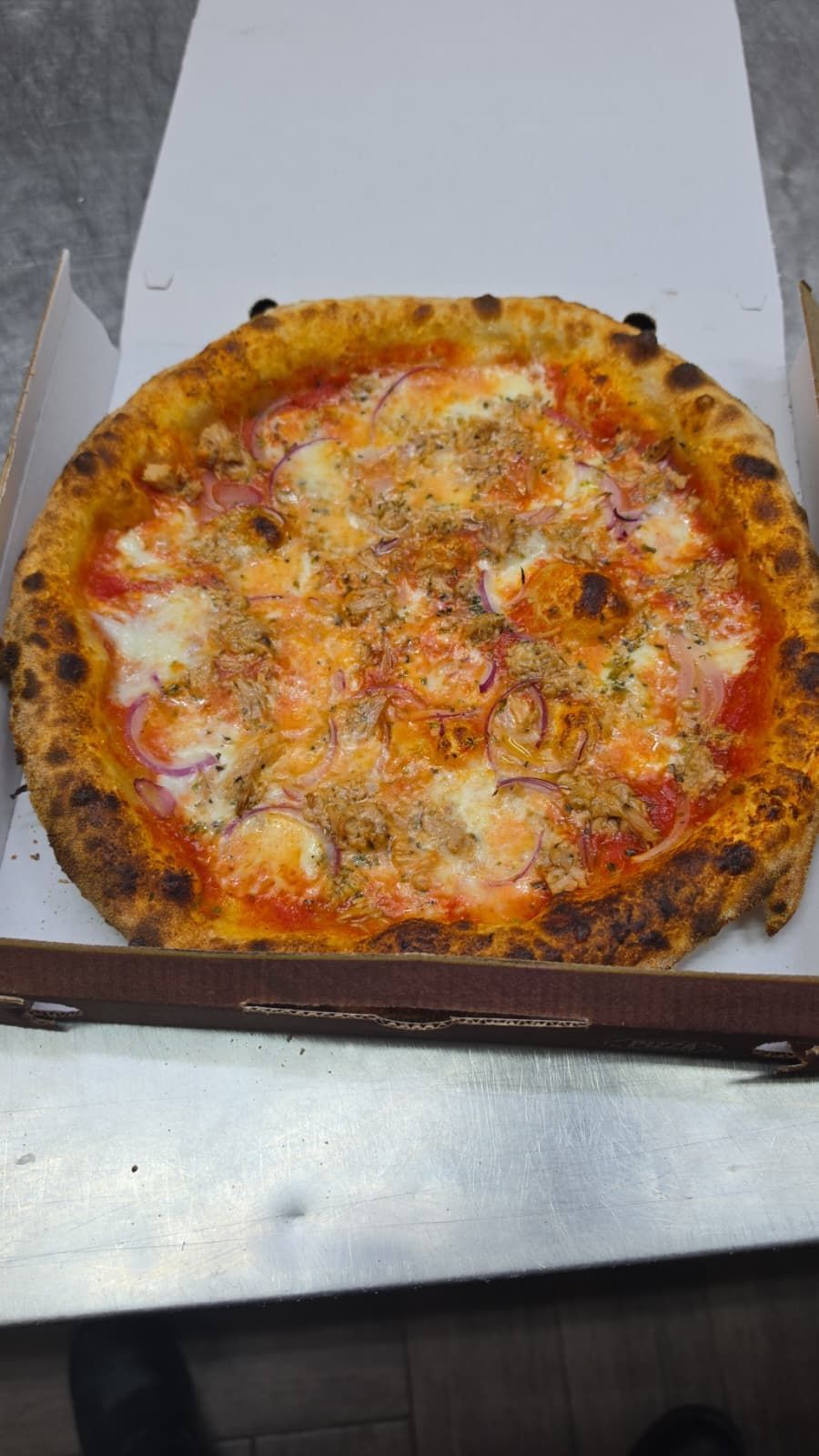 Pizza al formaggio in una scatola di cartone bianca aperta su un bancone
