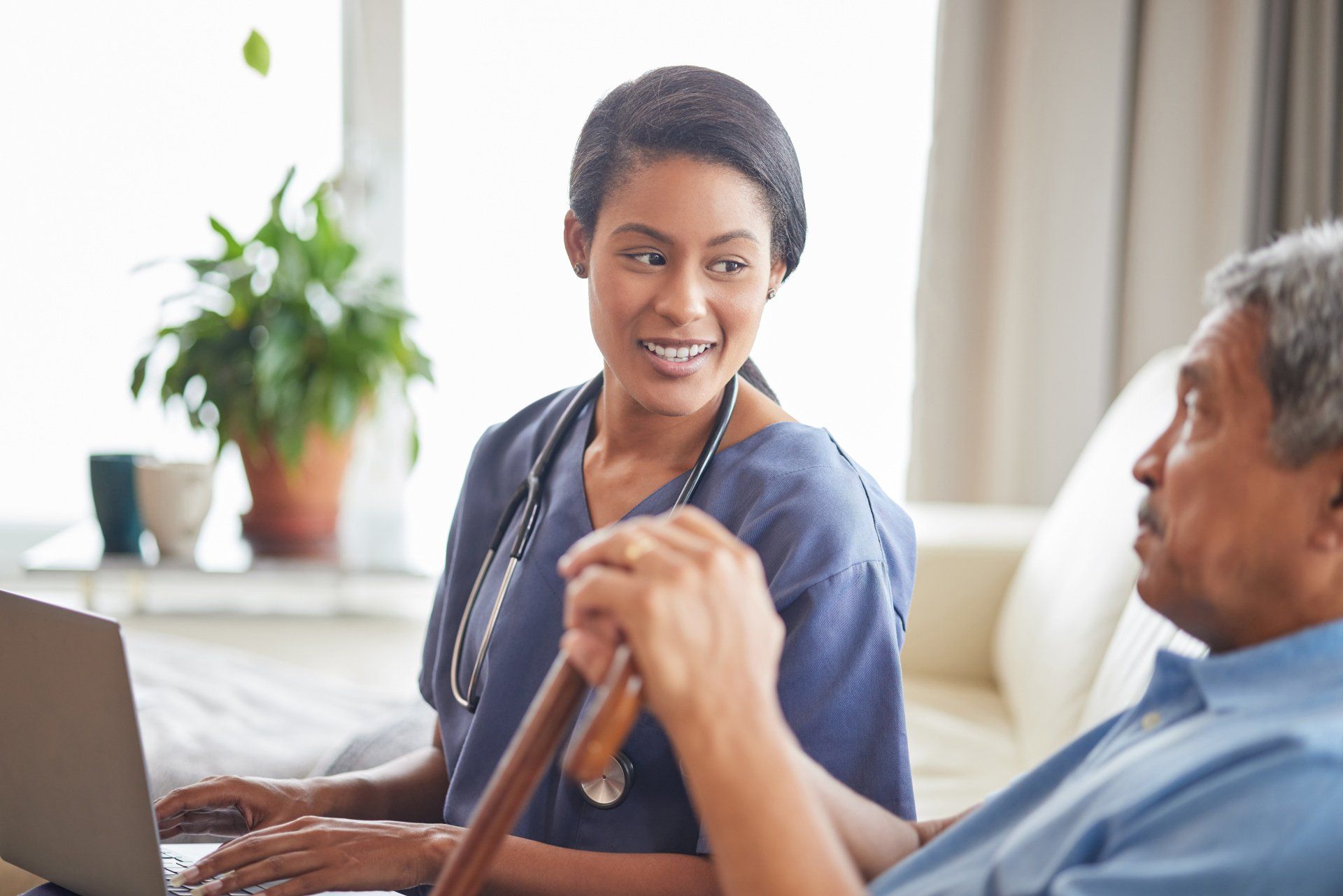 caregiver talking with an elderly man on the couch