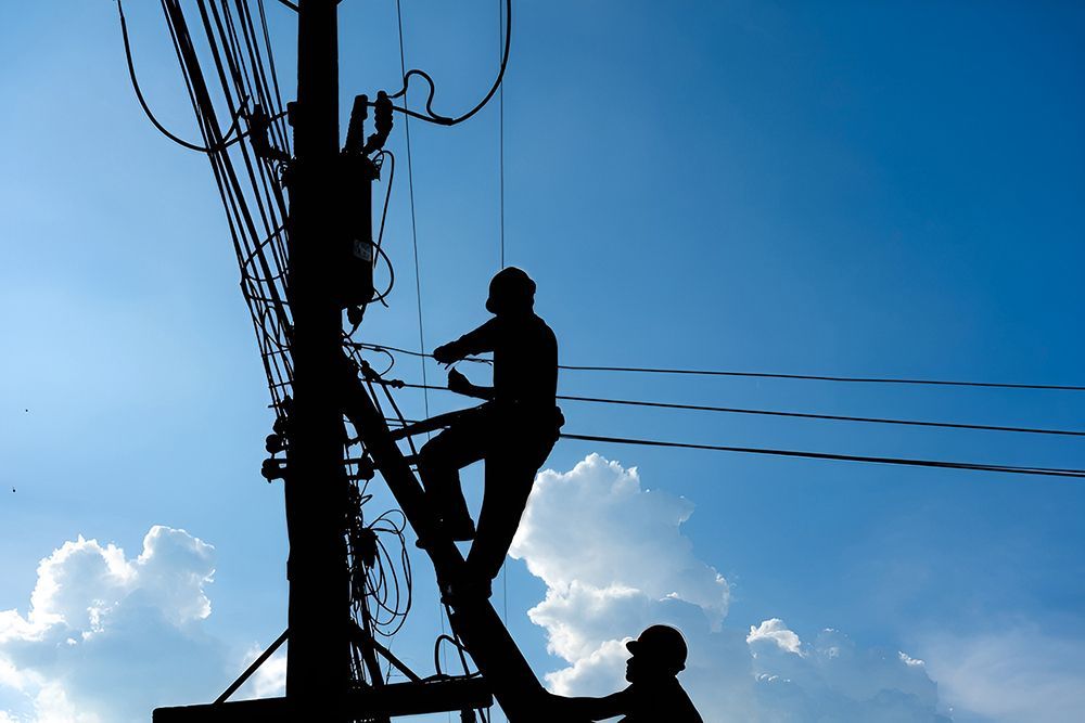 Silhouette of Two Utility Workers on a Power Pole — Gold City Solar & Electrical in Cooroy, QLD