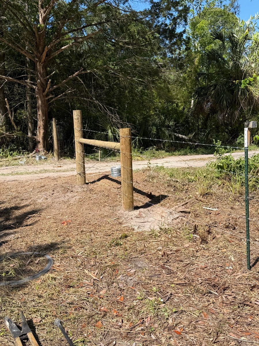 Wooden fence posts in a sunny wooded yard with leaf-covered ground