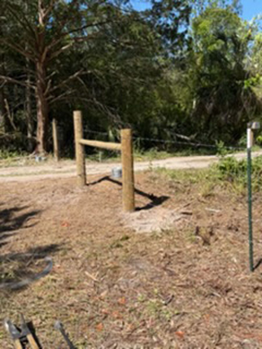 Wooden fence posts beside a dirt path in a wooded outdoor area