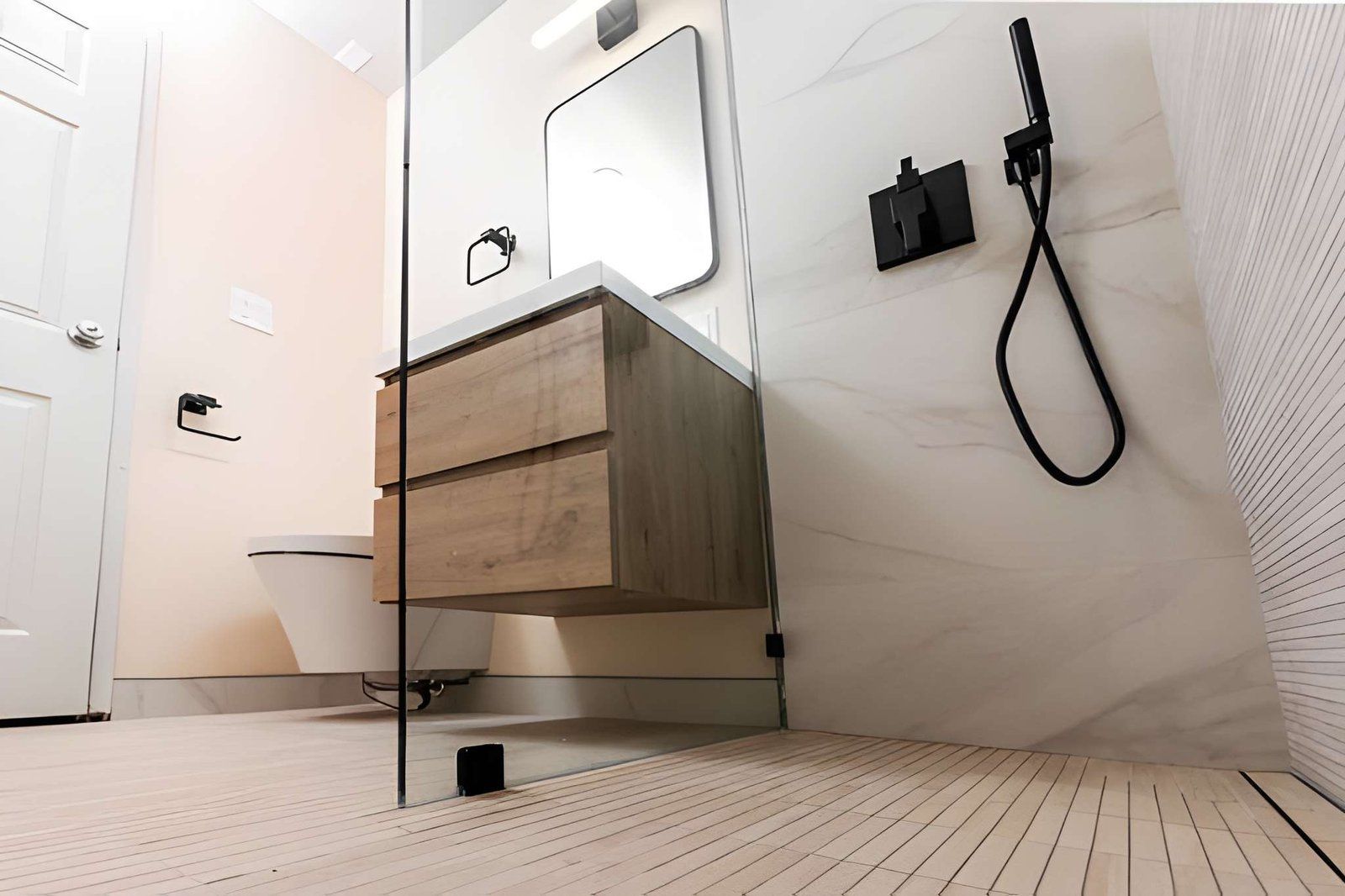 Modern bathroom with a floating wood vanity, wall mirror, and black shower fixtures on white tile.
