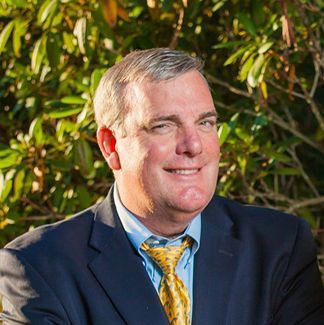 a man in a suit and tie is smiling for the camera .