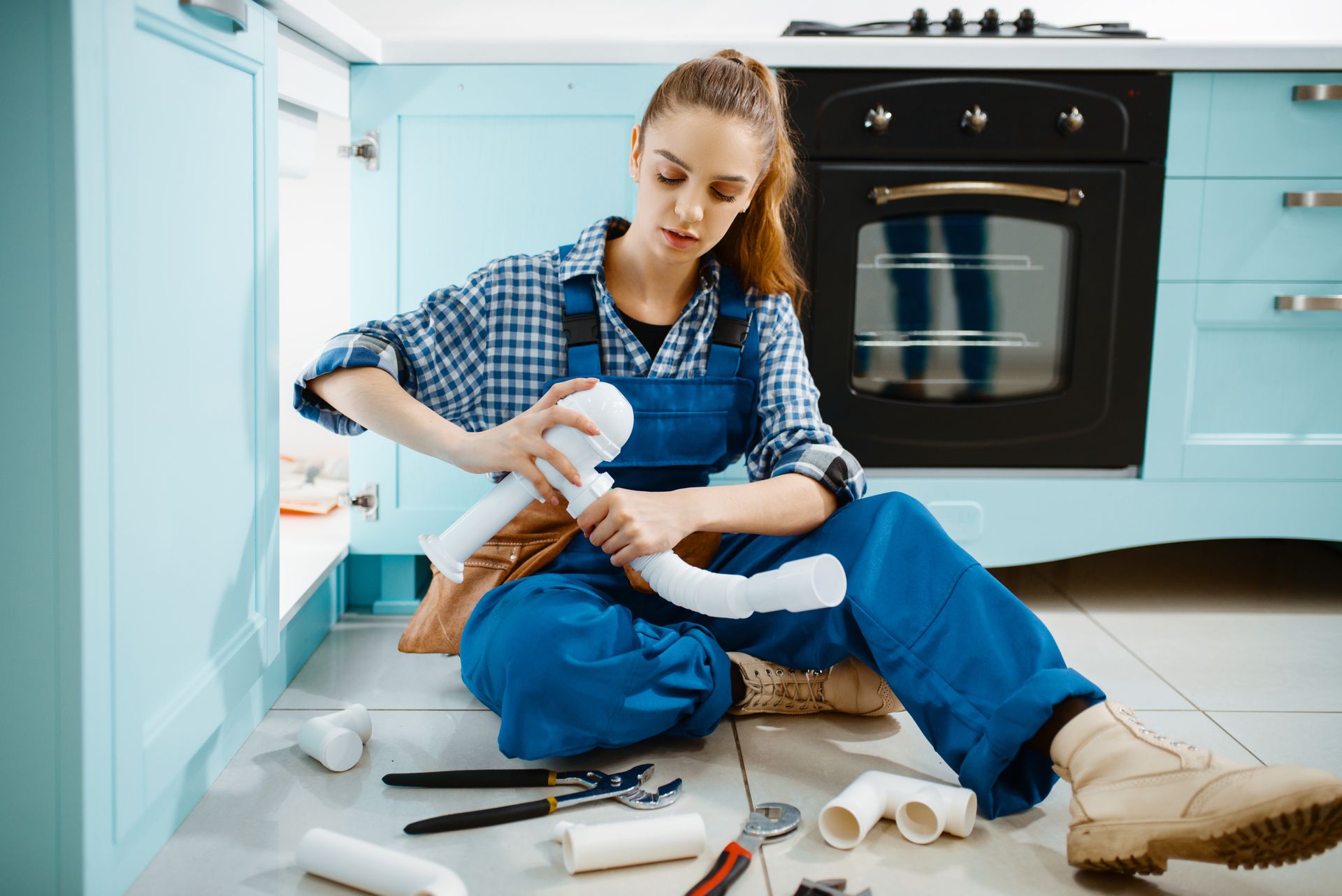 Female plumber fixing problem with drain pipe.