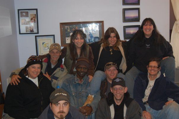 Group of smiling people posing indoors in front of framed wall art.