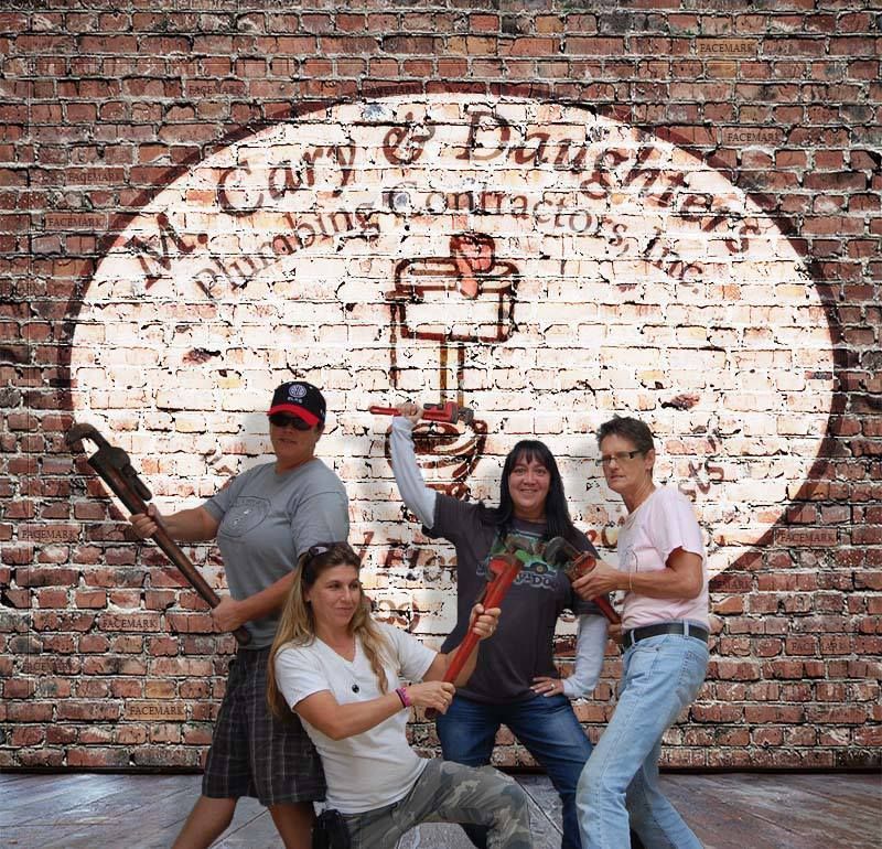 Four people posing with a giant spoon and fork in front of a brick wall mural