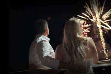 A man and a woman are watching fireworks in the night sky.