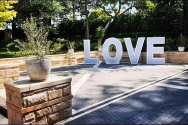 A large white love sign is sitting in a parking lot.