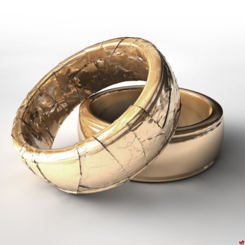Two gold wedding rings, one cracked and damaged, lying on a white surface. Infidelity Private Investigator Gallatin, TN