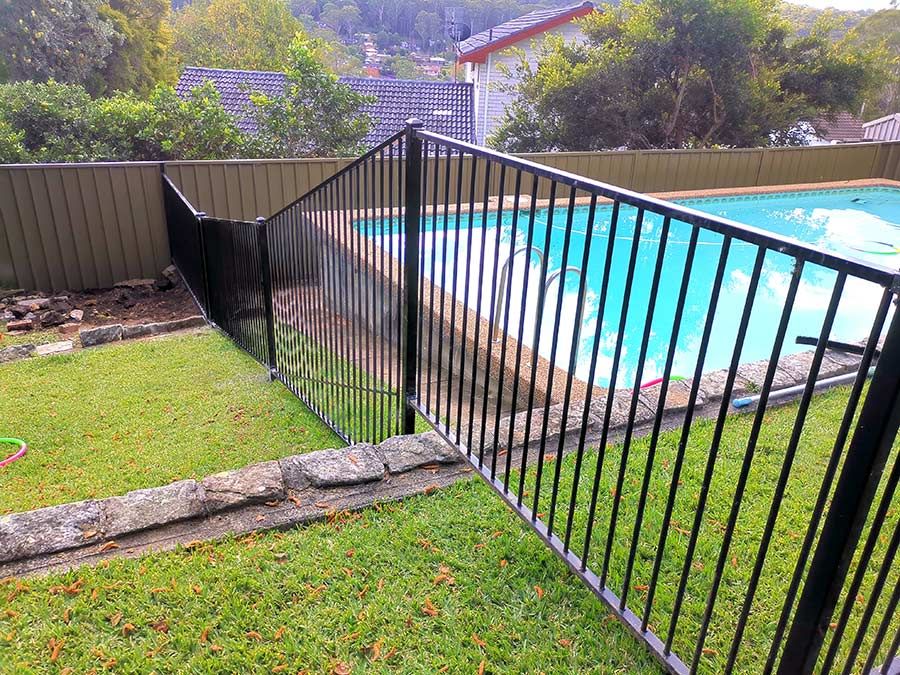 A swimming pool with a green umbrella and chairs around it — WeFence in Lisarow, NSW