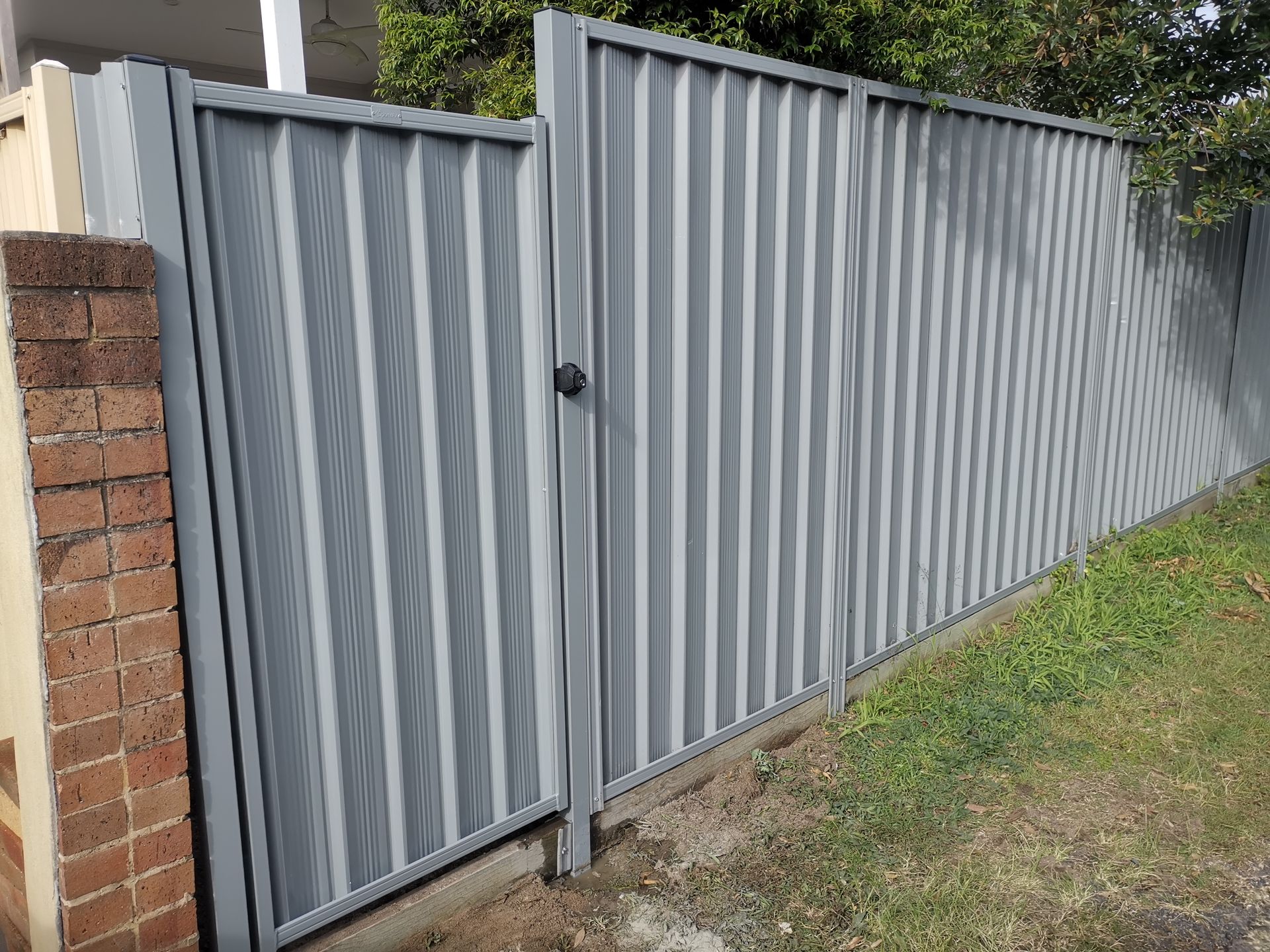 A gray metal fence is sitting next to a grassy path — WeFence in Lisarow, NSW