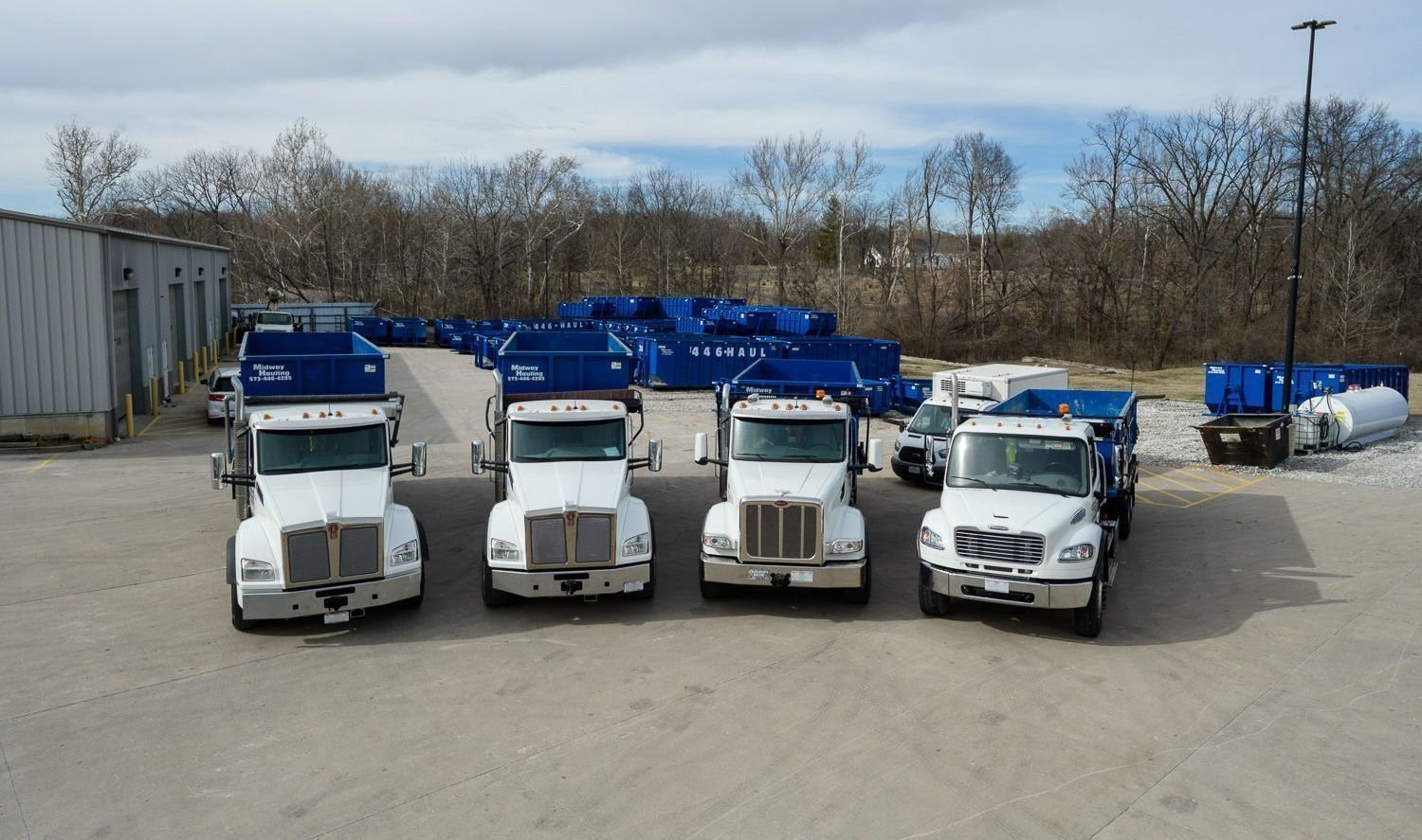 A group of trucks parked in a parking lot — Columbia, MO — Midway Hauling Containers & Roll-Offs