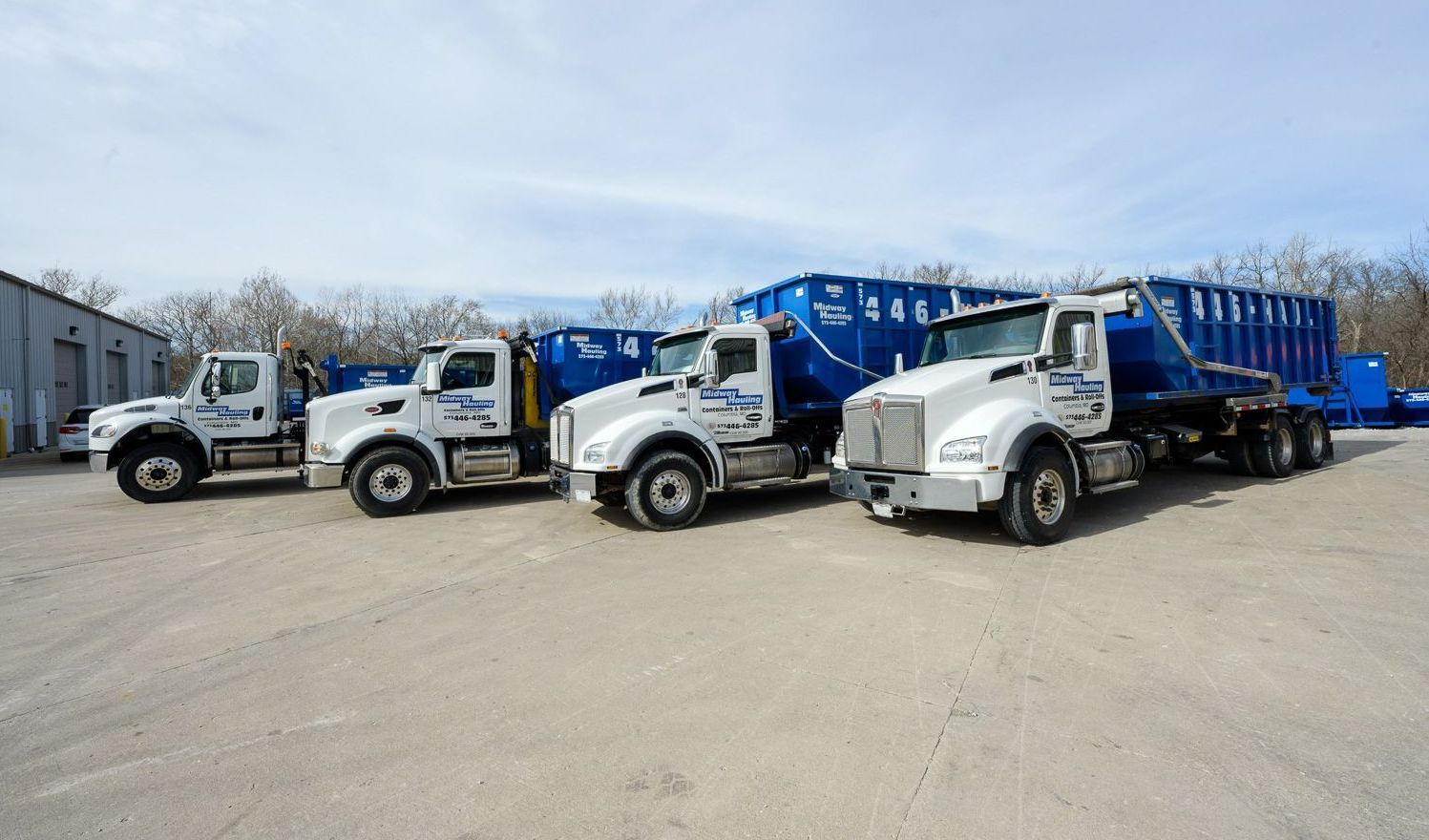 Side view of trucks parked in a parking lot — Columbia, MO — Midway Hauling Containers & Roll-Offs