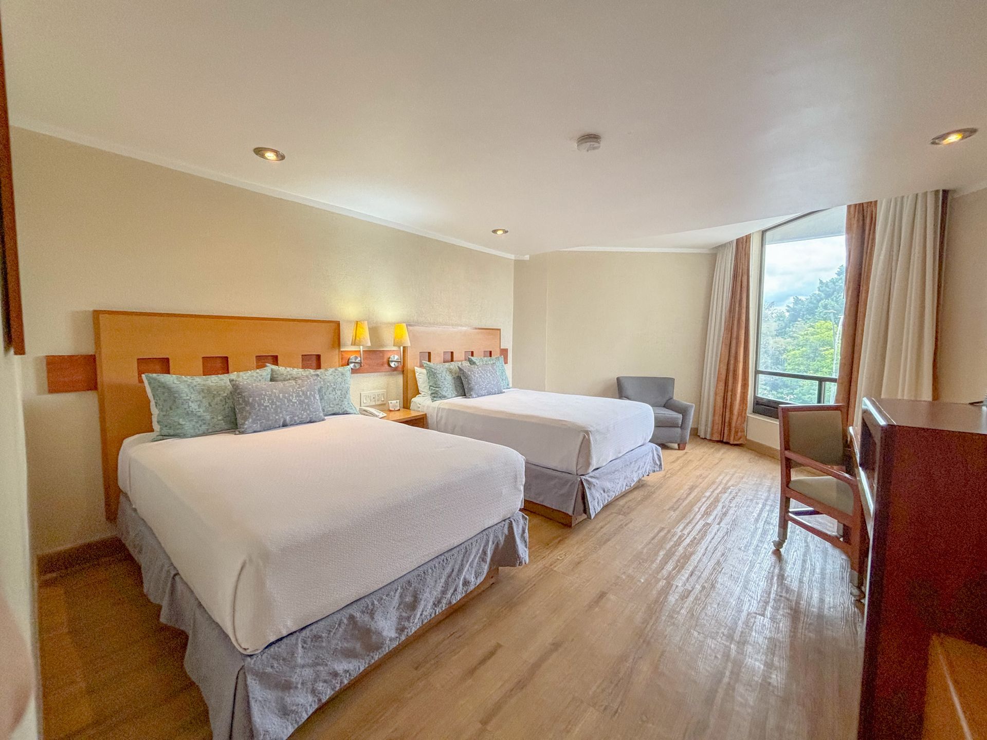 Una habitación de hotel luminosa y moderna con dos camas tamaño queen,