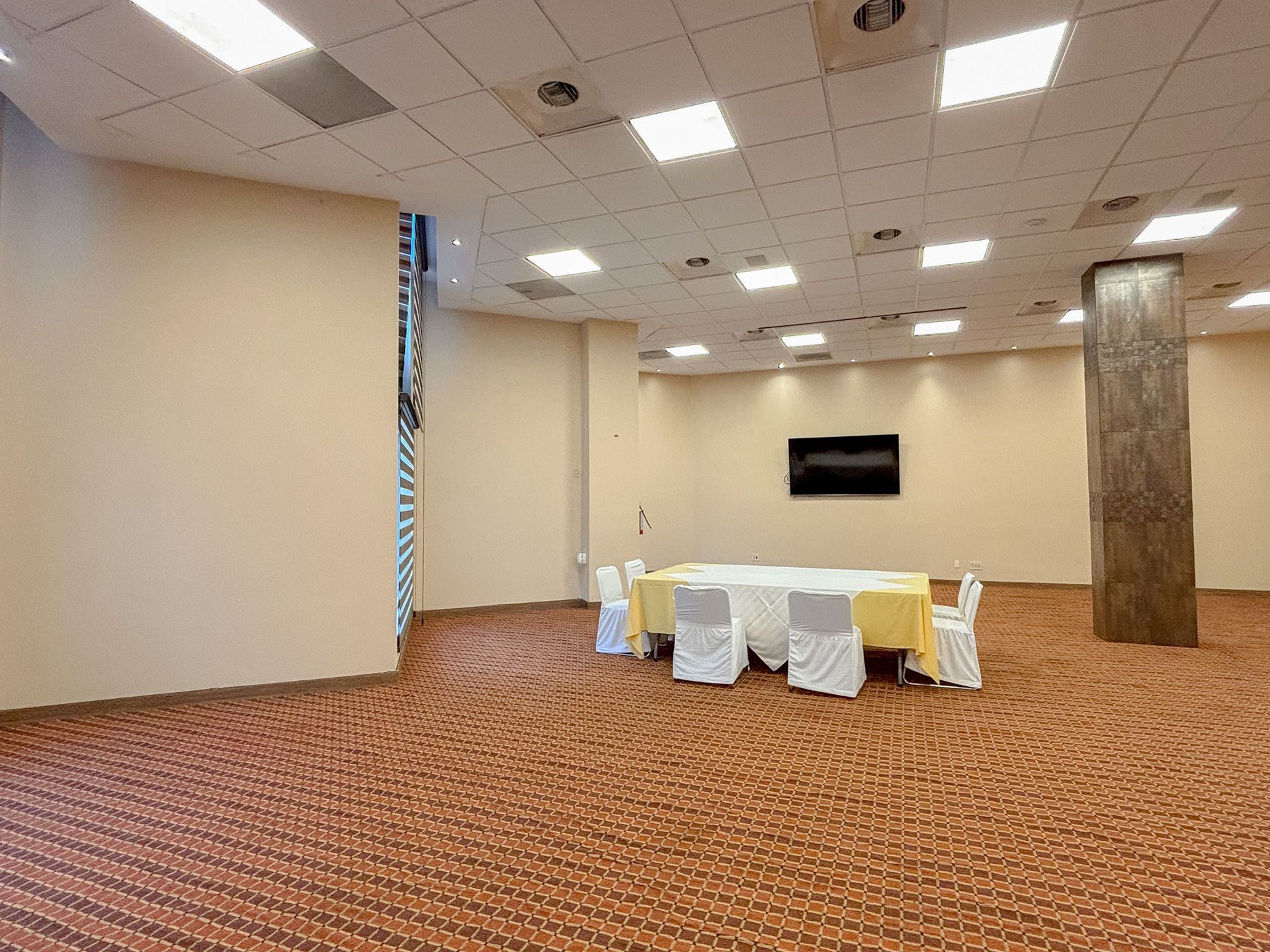 Una sala de conferencias con una mesa, sillas y paredes de color beige