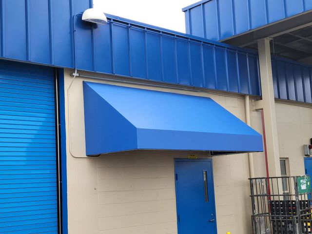 Blue awning over a blue door on a beige building exterior