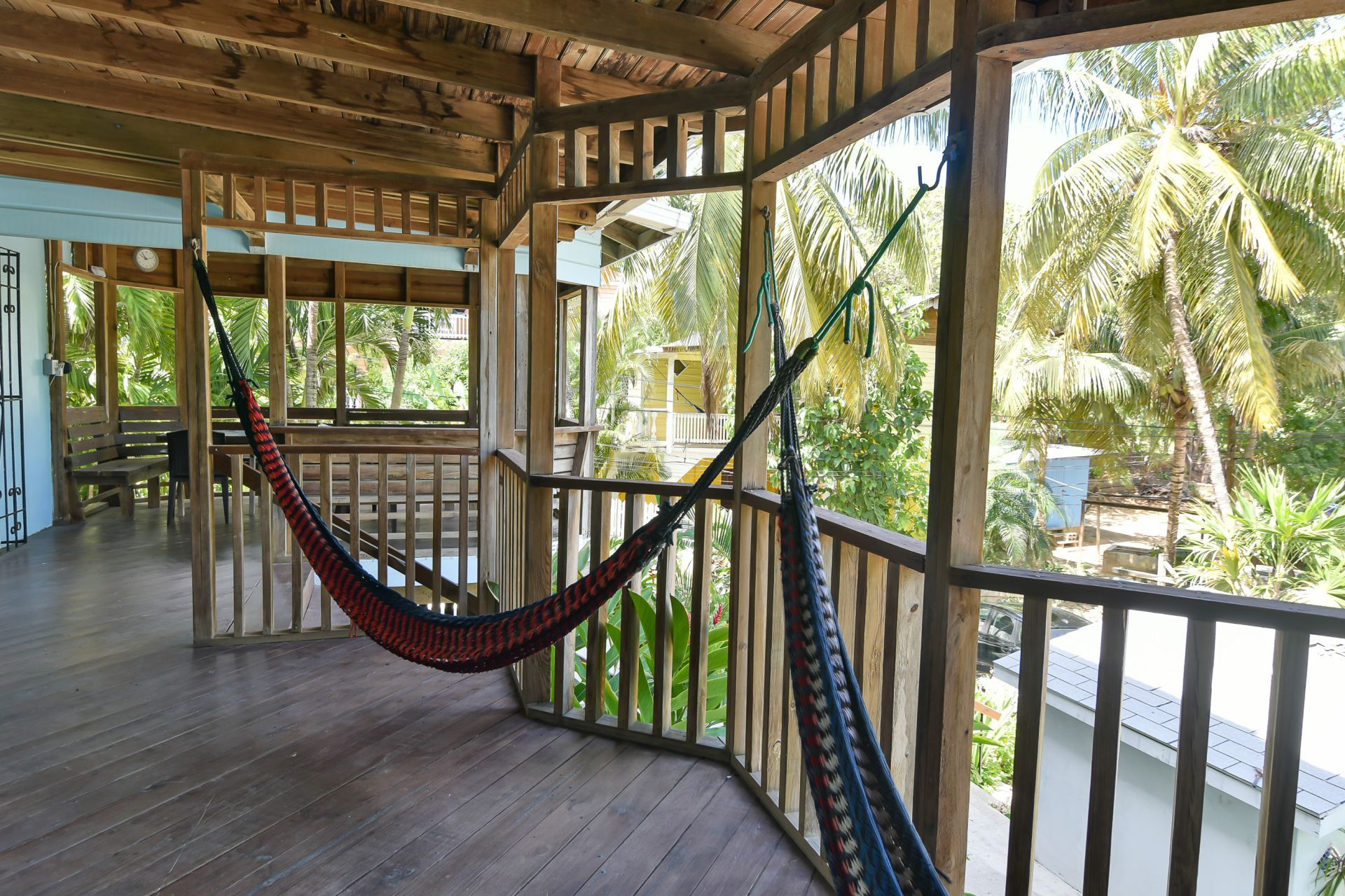 Wooden porch with hammocks overlooking tropical greenery.