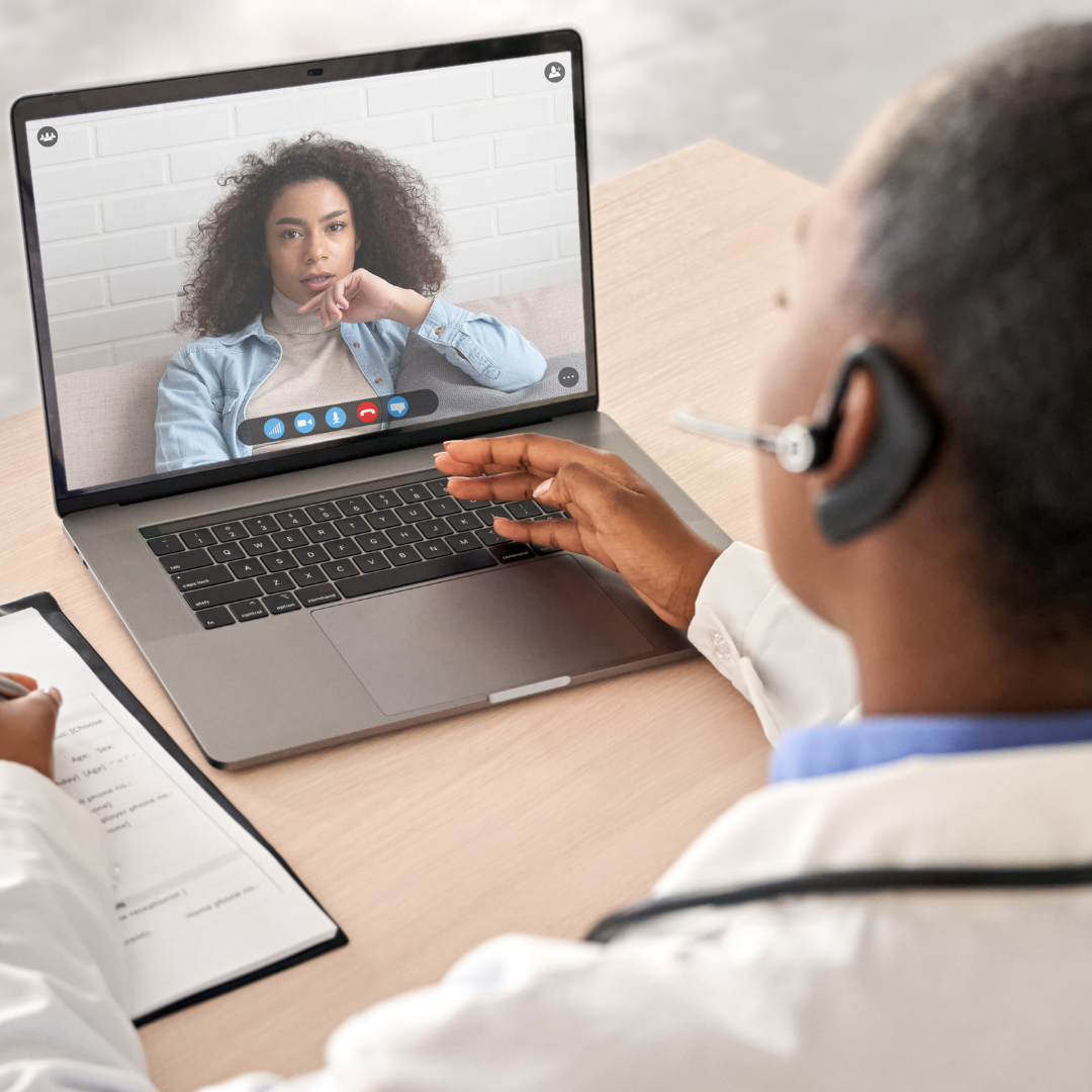 A doctor is having a video call with a patient on a laptop.