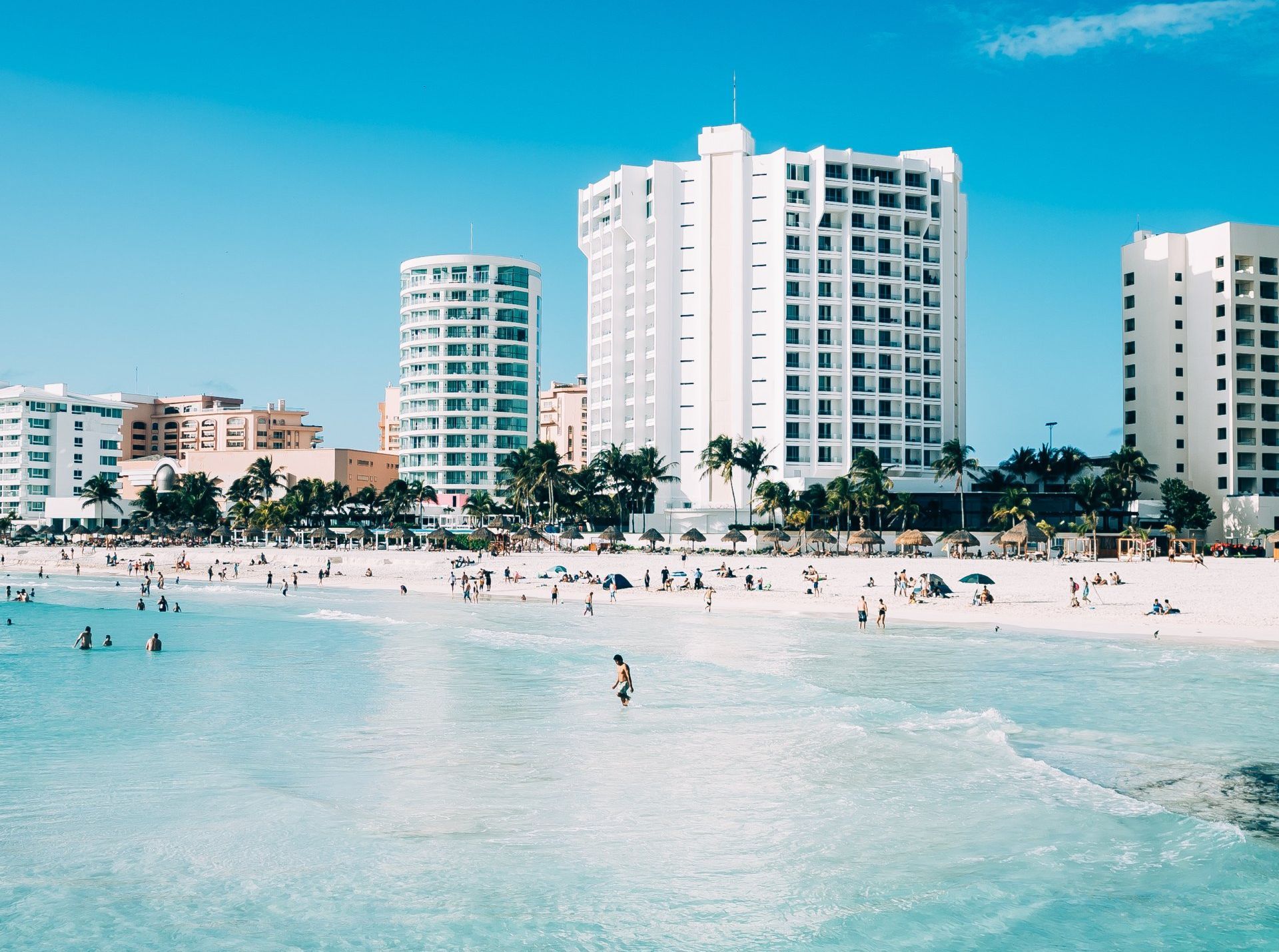 A beach with a lot of people and buildings in the background.
