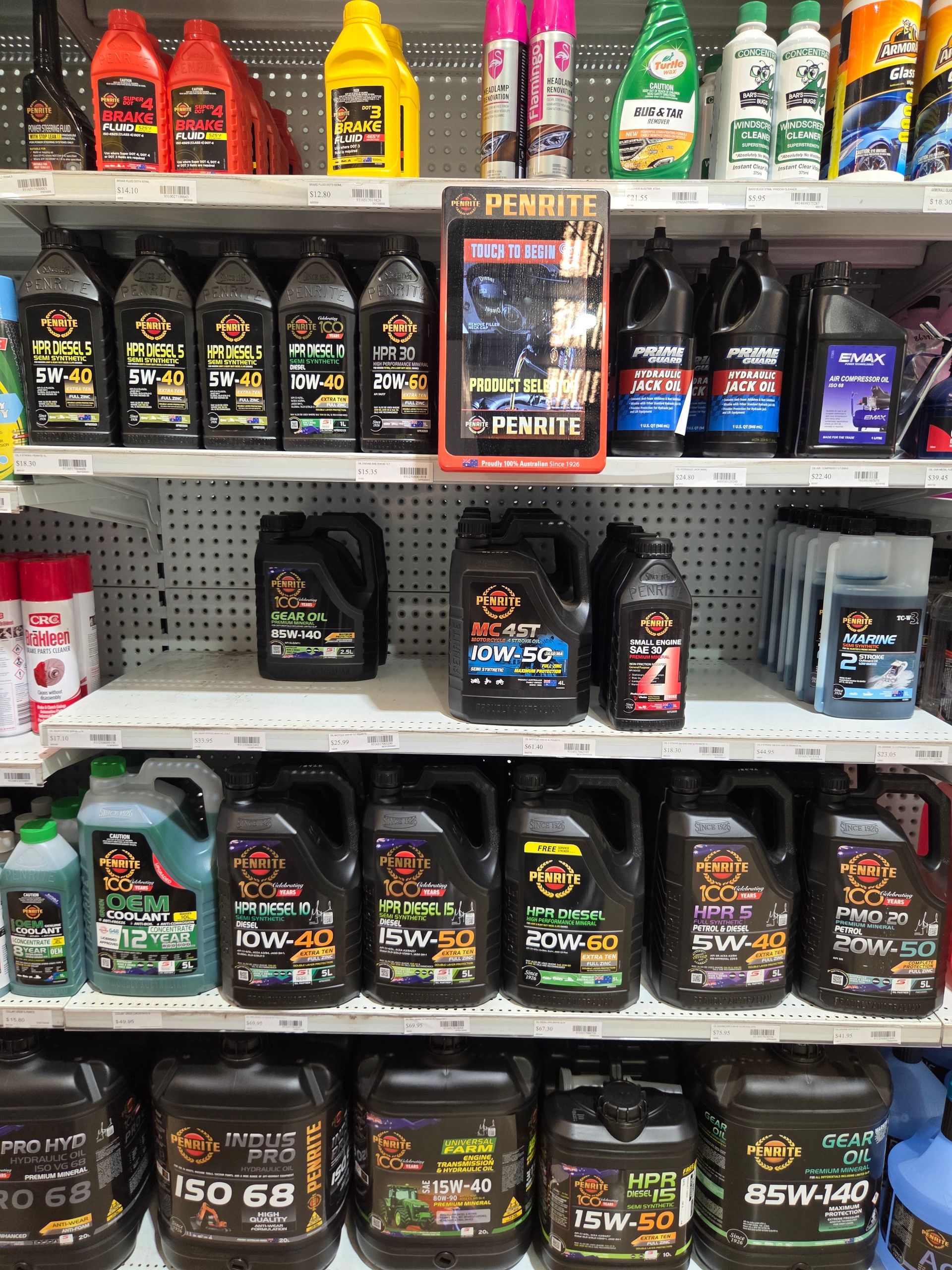 Store shelf stocked with motor oils and car fluids in assorted black, red, yellow, and blue bottles — Humpty Doo Hardware in Humpty Doo, NT