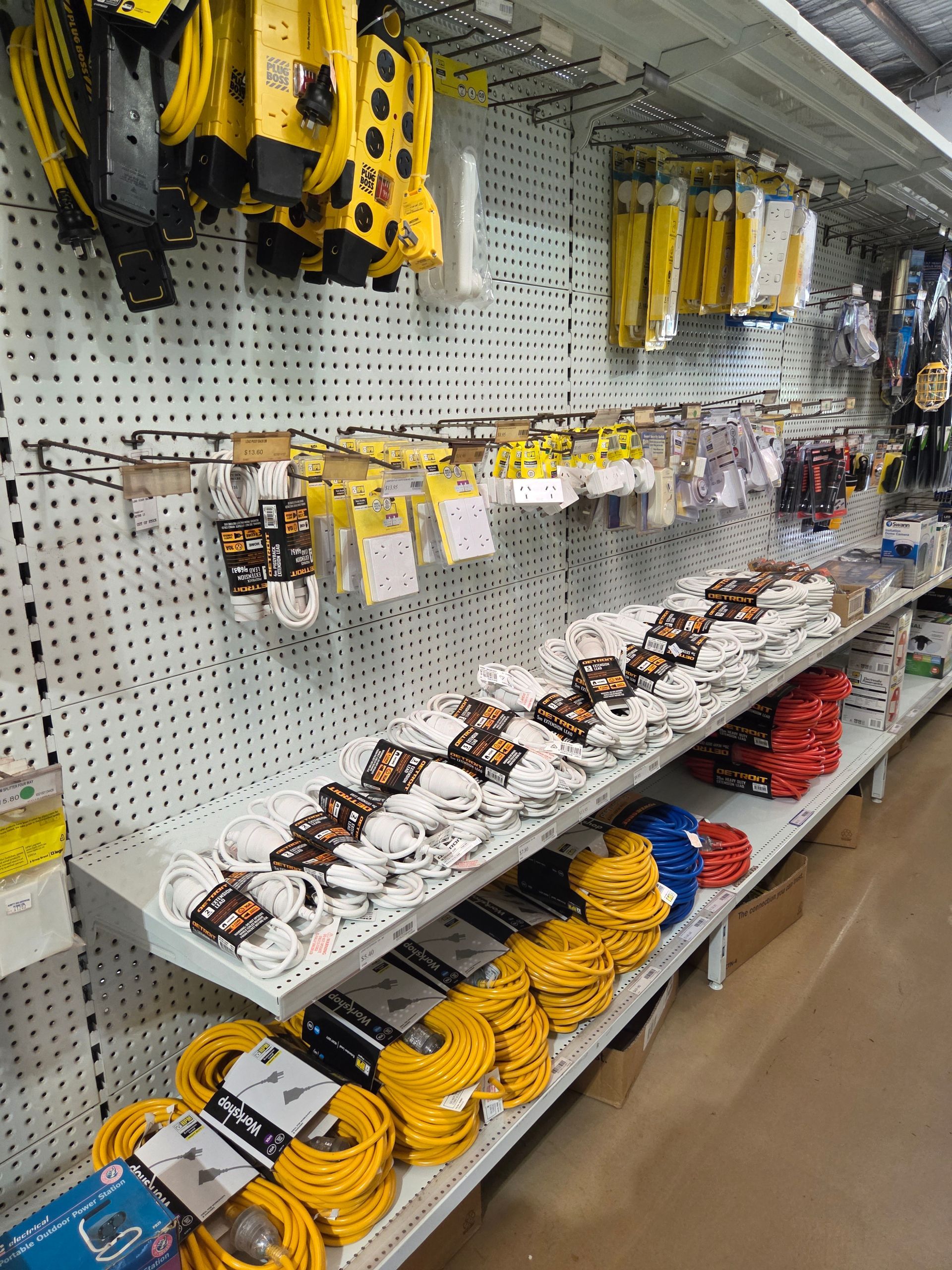 Hardware store aisle with pegboard display of yellow and black tools, cables, and accessories — Humpty Doo Hardware in Humpty Doo, NT