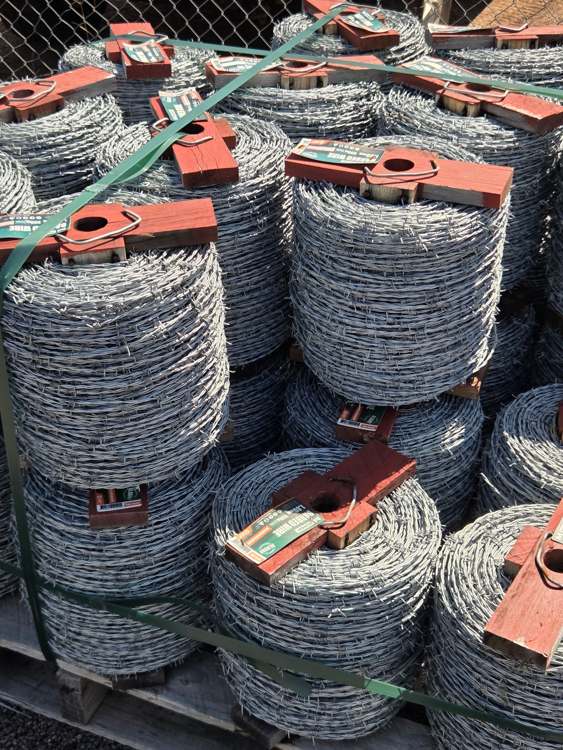 Stacks of coiled metal wire bundles secured with red straps in a storage yard — Humpty Doo Hardware in Humpty Doo, NT