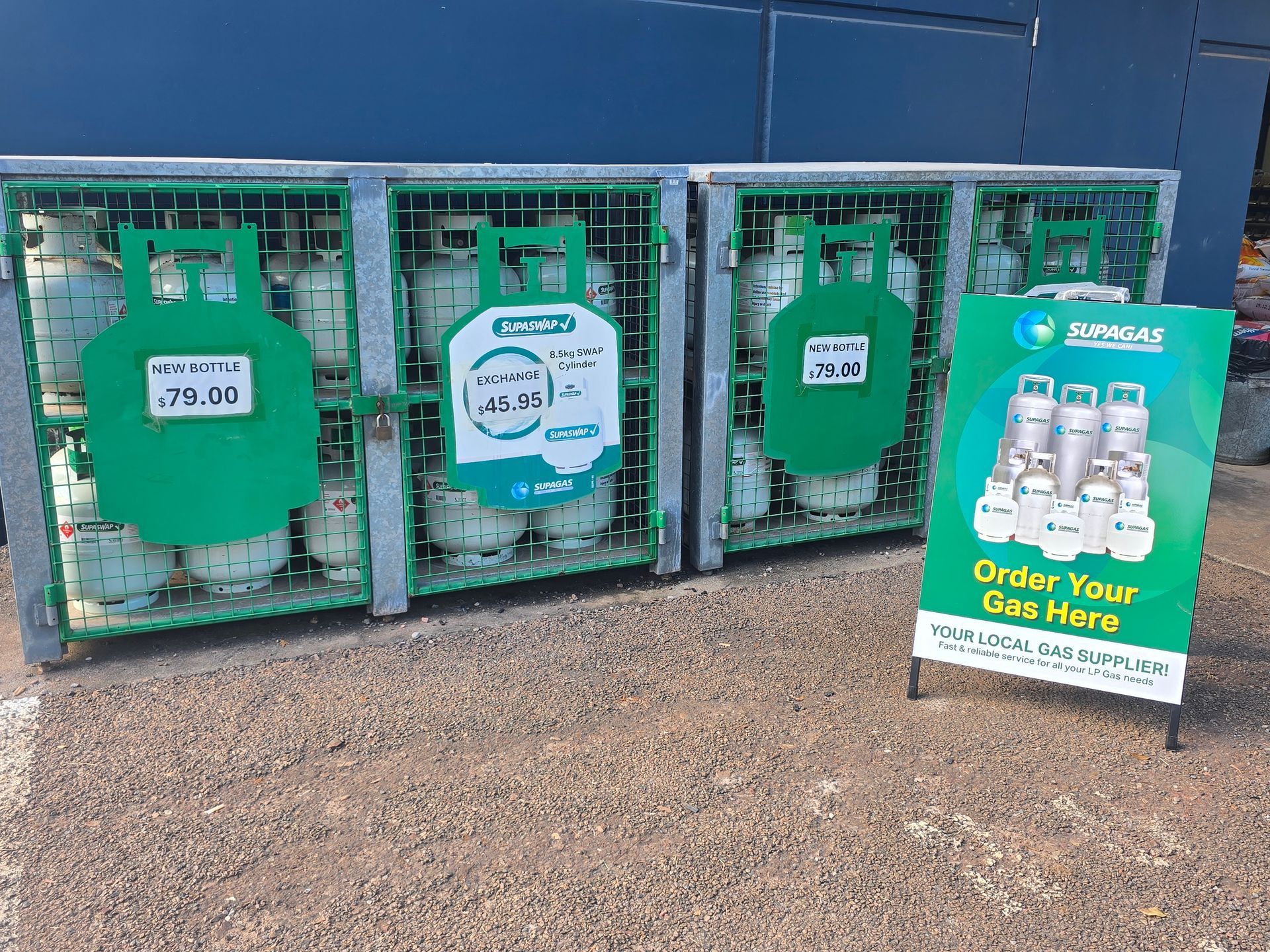 Three green propane exchange cages beside a sign reading “Order Your Gas Here” outdoors. — Humpty Doo Hardware in Humpty Doo, NT