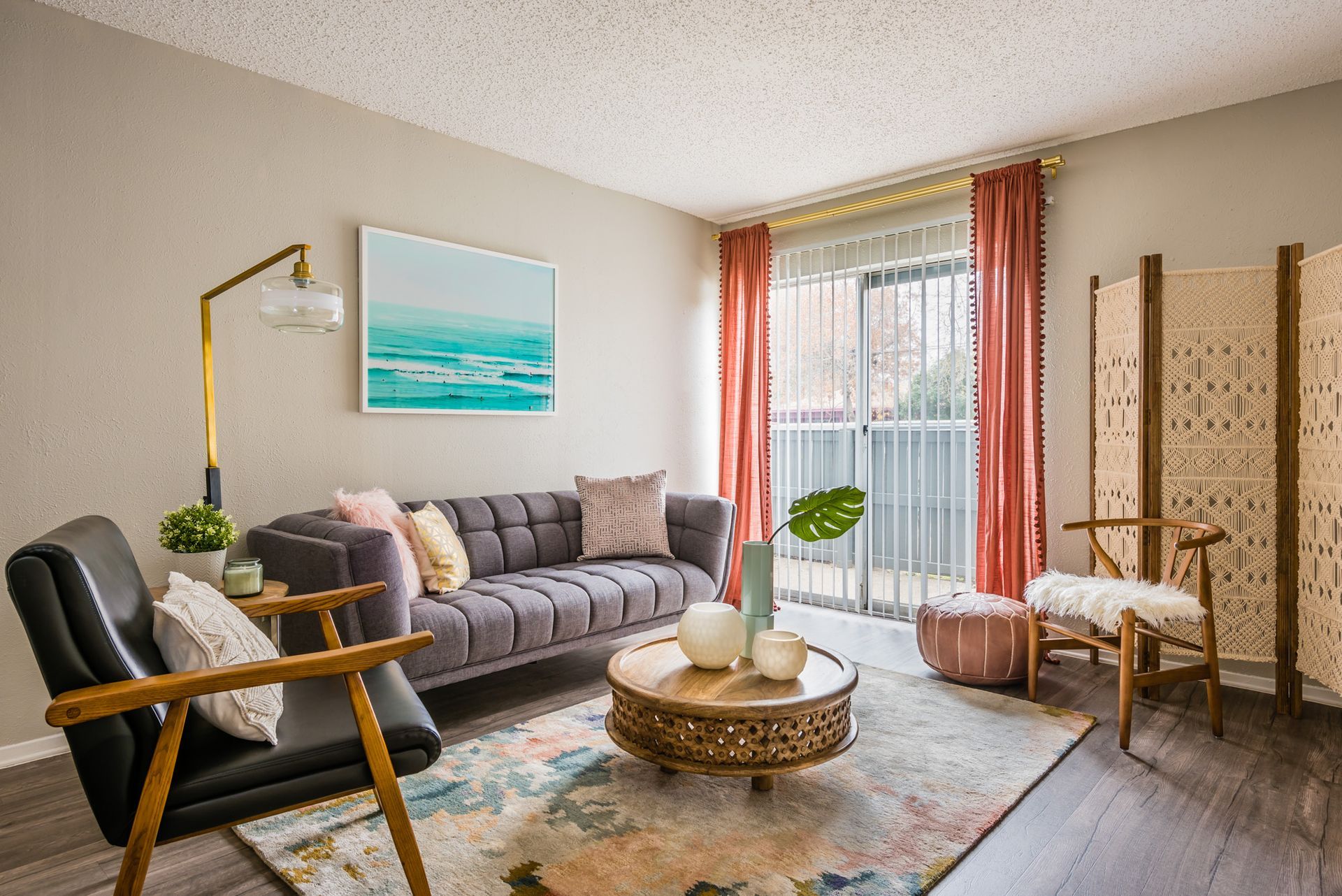 Living room with gray sofa, gold lamp, artwork, and pink curtains.