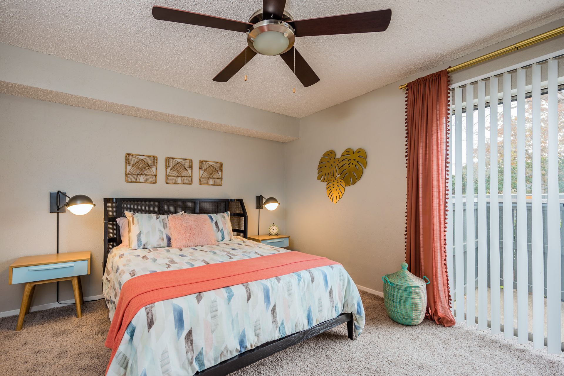 Bedroom with bed, nightstands, ceiling fan, and sliding glass door with a coral curtain.