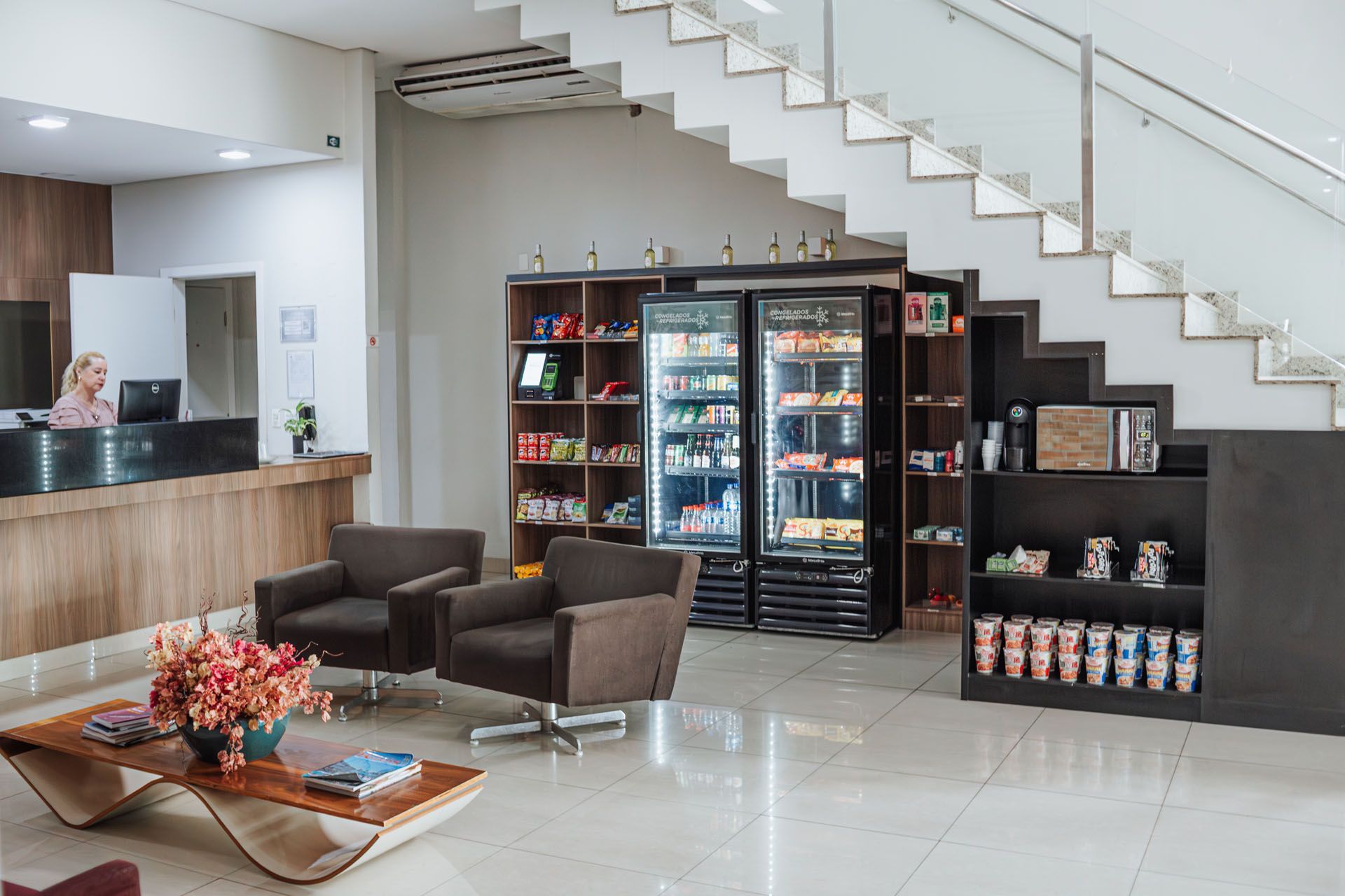 Hall de entrada moderno com assentos, frigobar e escada em um interior claro e branco.