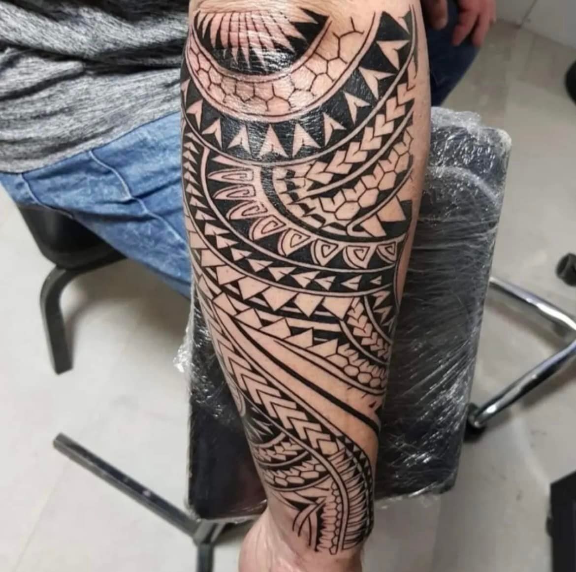 Op een onderarm is een gedetailleerde, in zwarte inkt uitgevoerde tribale tatoeage in Polynesische stijl te zien, met geometrische patronen en chevronmotieven.