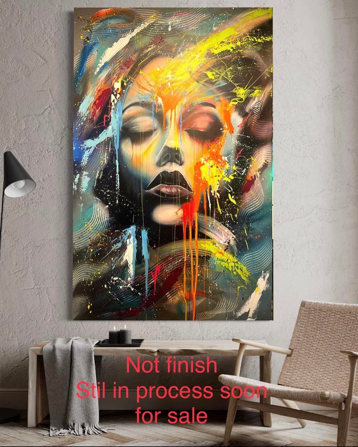 Een levendig, abstract portret met druipende verf in geel, rood en blauw, tentoongesteld in een moderne kamer boven een bank.