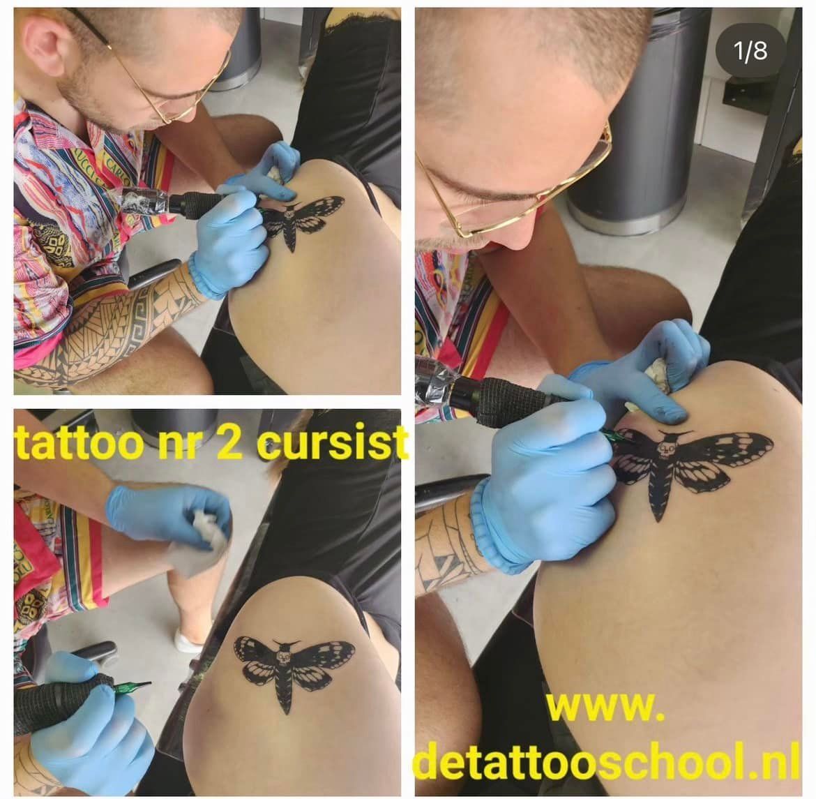 Een tatoeëerder met blauwe handschoenen tatoeert een mot op de huid van een klant. De tekst promoot de website van een tatoeëerschool.