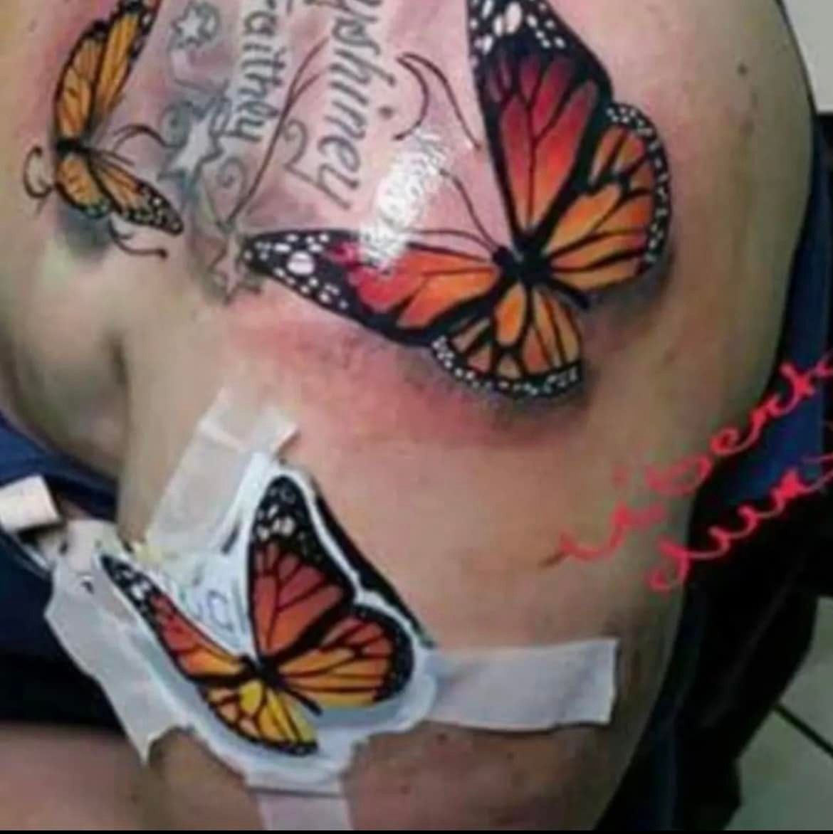 Tatoeages van monarchvlinders op iemands schouder, waarbij één vlinder als tijdelijke pleister is aangebracht.