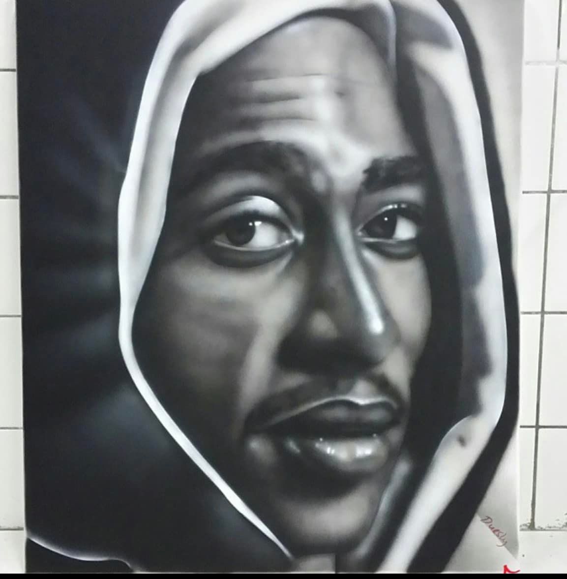 Een monochroom portret van een persoon in een kledingstuk met capuchon, die niet recht in het midden kijkt en een neutrale uitdrukking heeft.