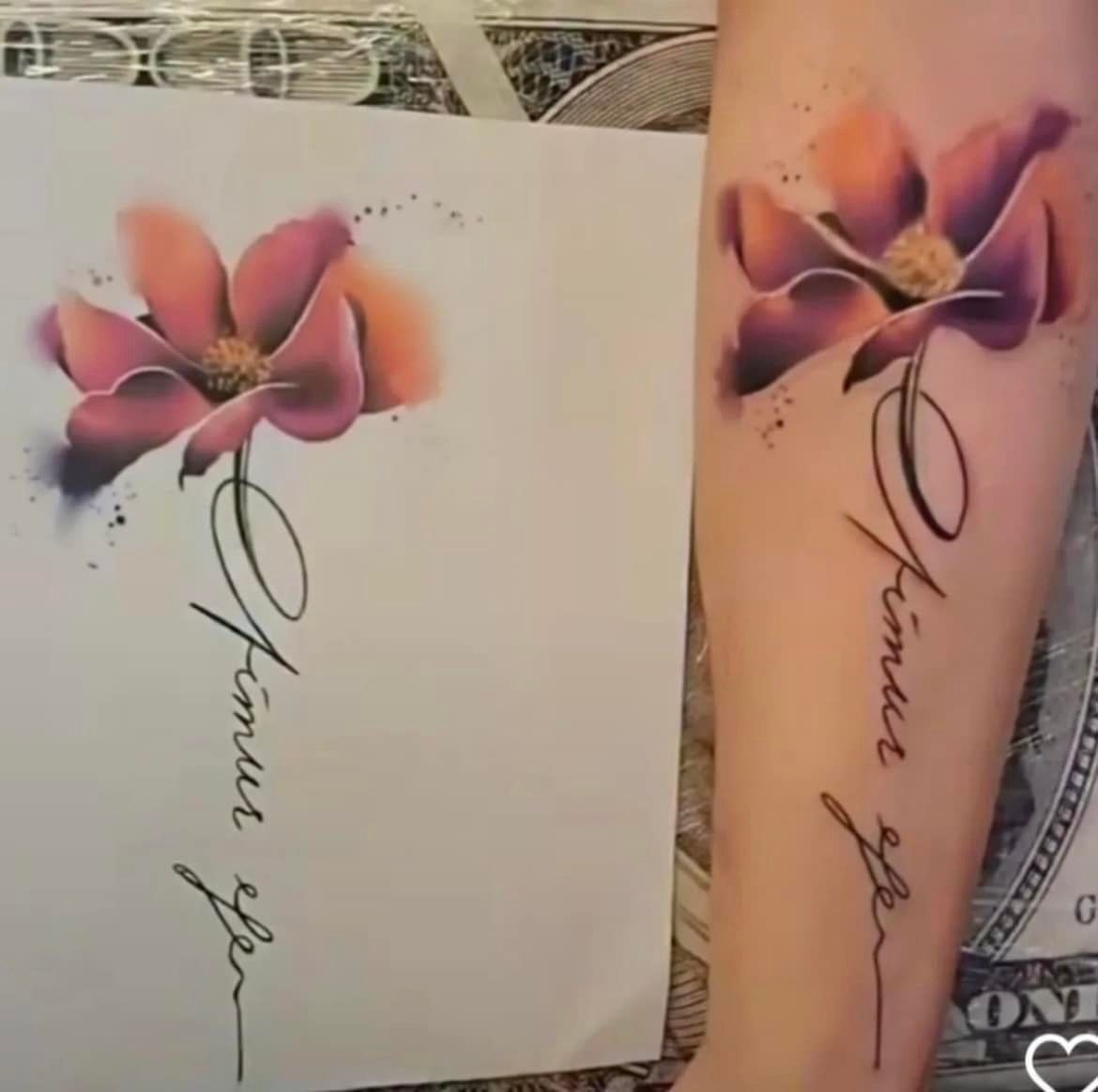 Een bloemtattoo in aquarel-stijl op een arm naast het originele kunstwerk, met elegant cursief schrift onder de bloemblaadjes.