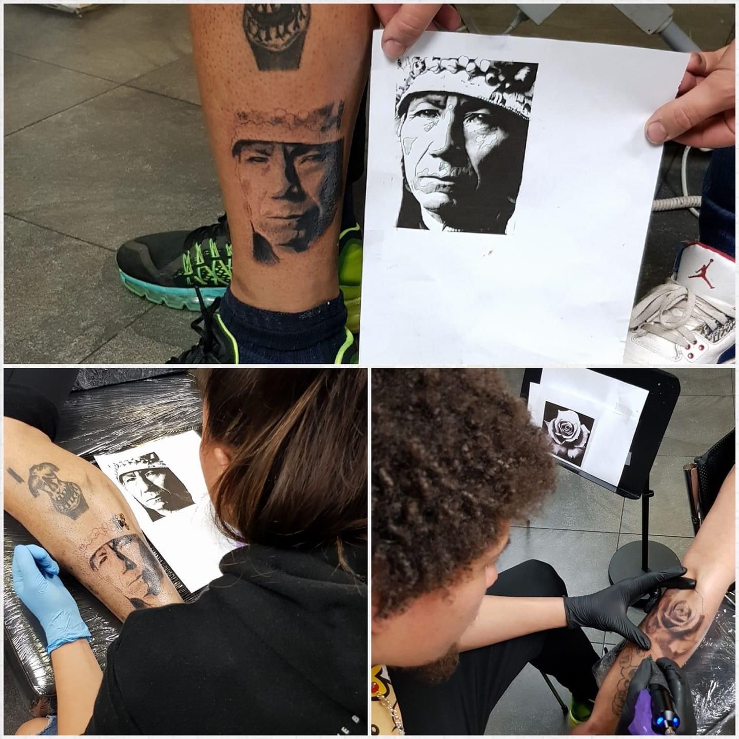 Een tatoeëerder werkt aan een portrettatoeage op de kuit, waarbij hij een afgedrukte schets als referentie gebruikt die tegen de huid wordt gehouden.