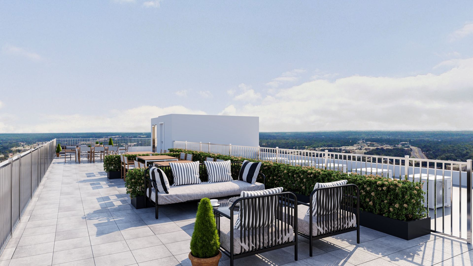 A rooftop terrace with lounge seating, striped cushions, and potted greenery, overlooking a distant landscape.
