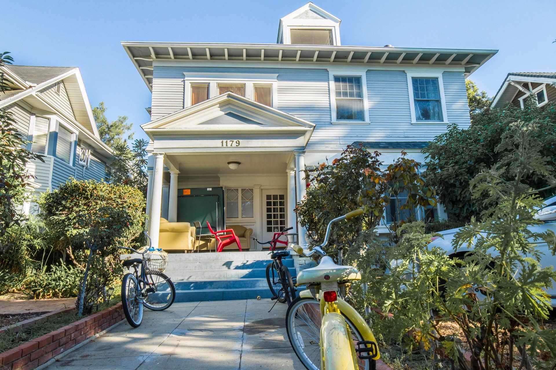 This image shows luxury house and three bycicles and a car in front of home