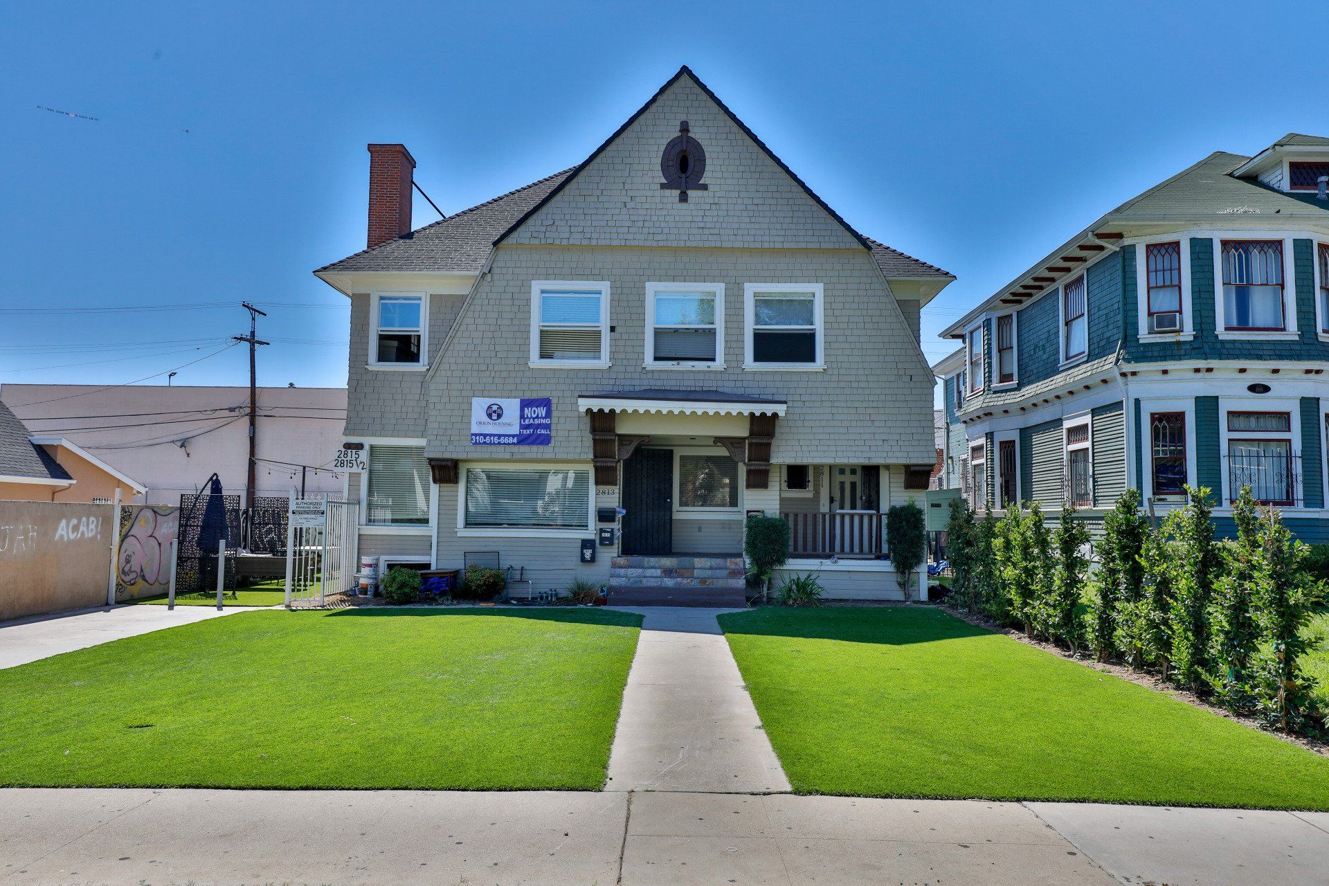 This image shows two house having blue and white color as well as greenery in front